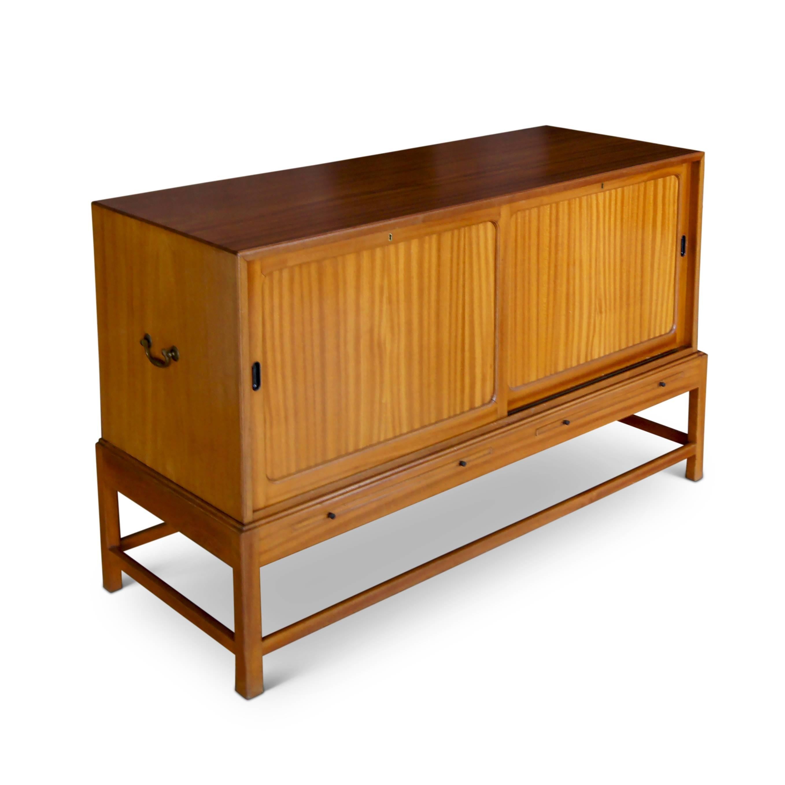 Sideboard, model no. 4122, designed by Kaare Klint (1888-1954) consisting of a cabinet with two sliding doors opening to reveal adjustable shelf or drawers with retractable tray surfaces under each side, on an articulated stand (cabinet and Stand