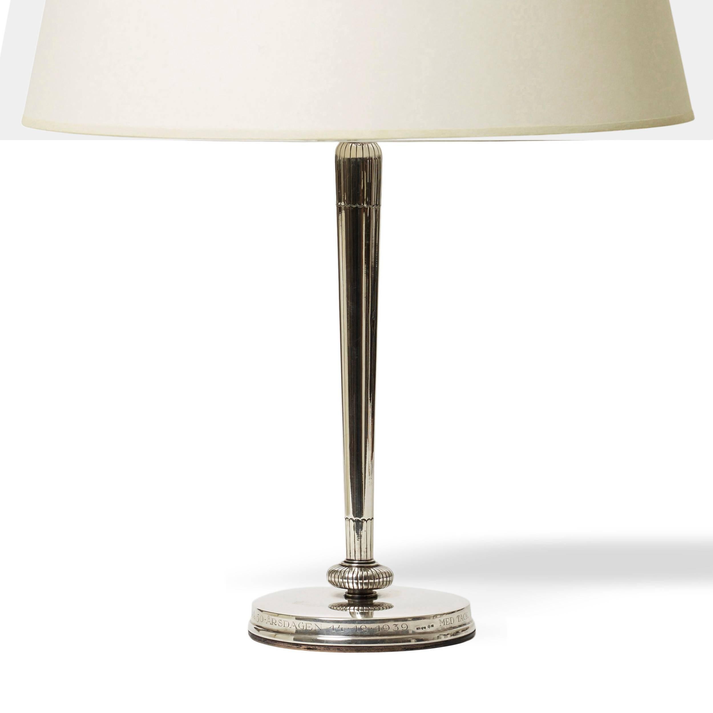 Pair of elegant and tailored Moderne style table lamps from the Carl Gustav Hallberg workshop, with vertical featuring a crisp taper and detailing around shoulder perched atop a disk fob detailed as a rosette on a round plinth, Sweden, 1937; Stamped