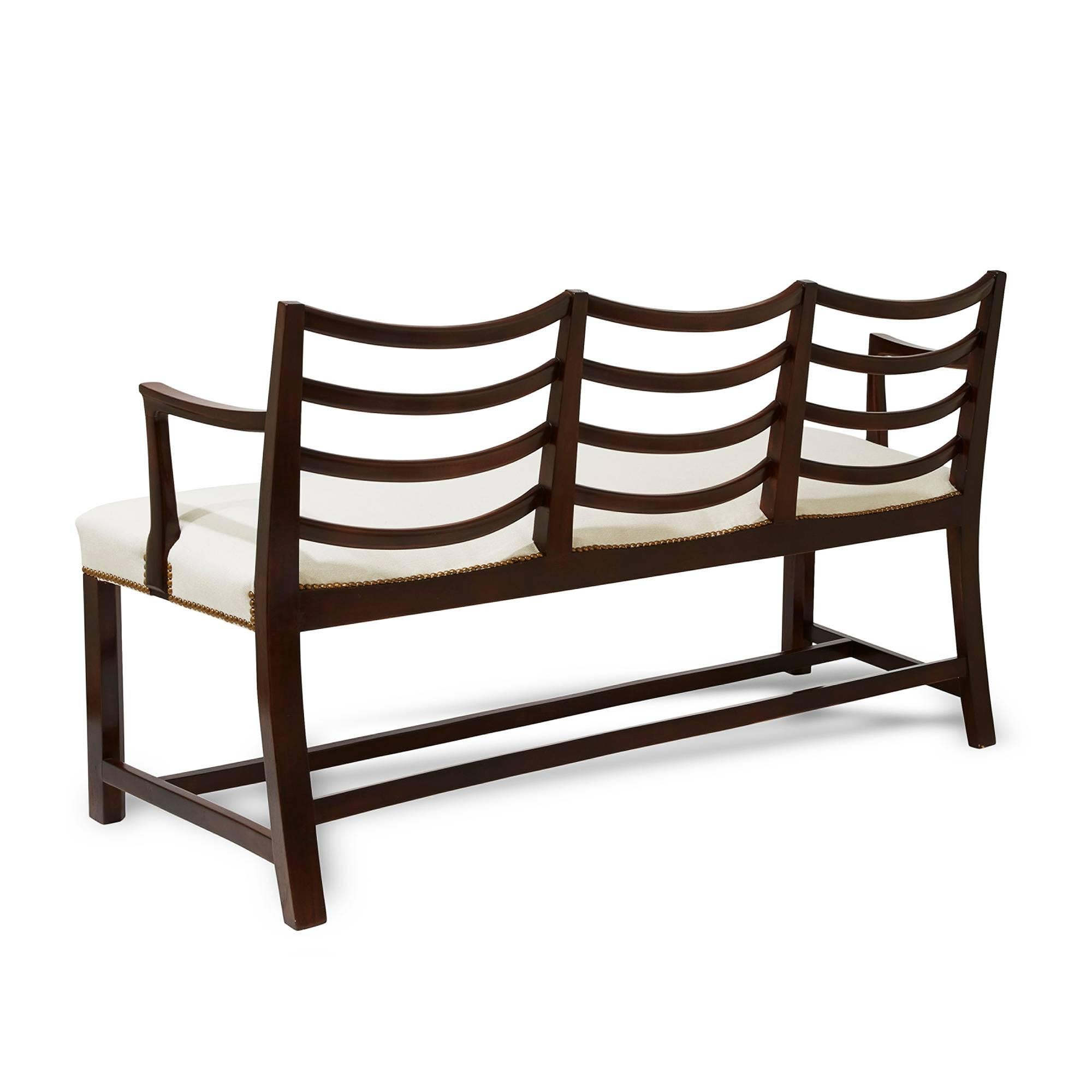 Sculptural three-seat bench settee by Fritz Hansen, an uncommon, possibly custom design with magnificently considered modeling, featuring repeated drapery lines, including “swag” back crests and splats and sinewy arms, in stained birch, Denmark,