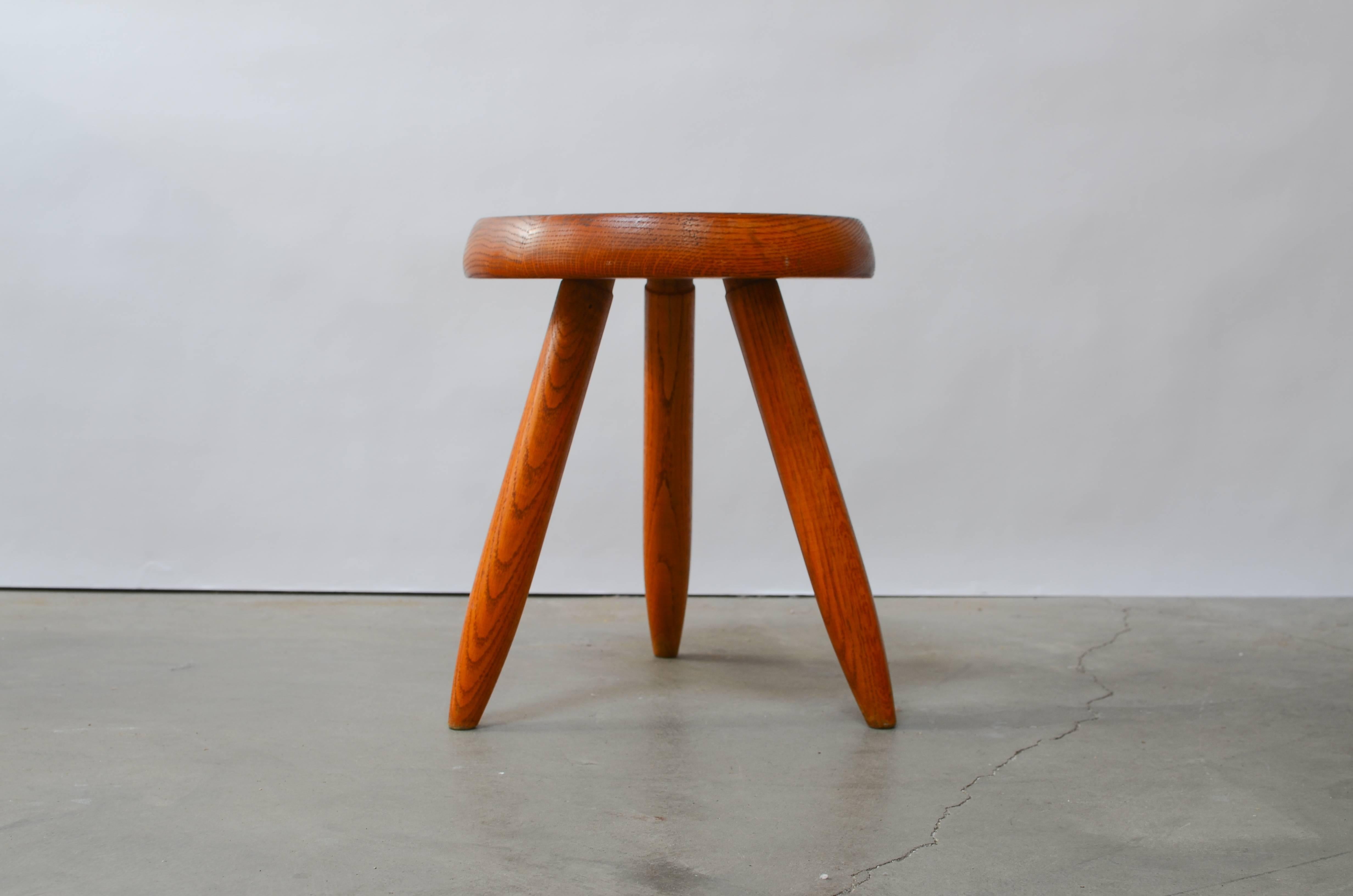 Early and rare oak tripod stool designed by Charlotte Perriand for Steph Simon, circa 1950, France. Stunning original patina with a beautiful wood grain.