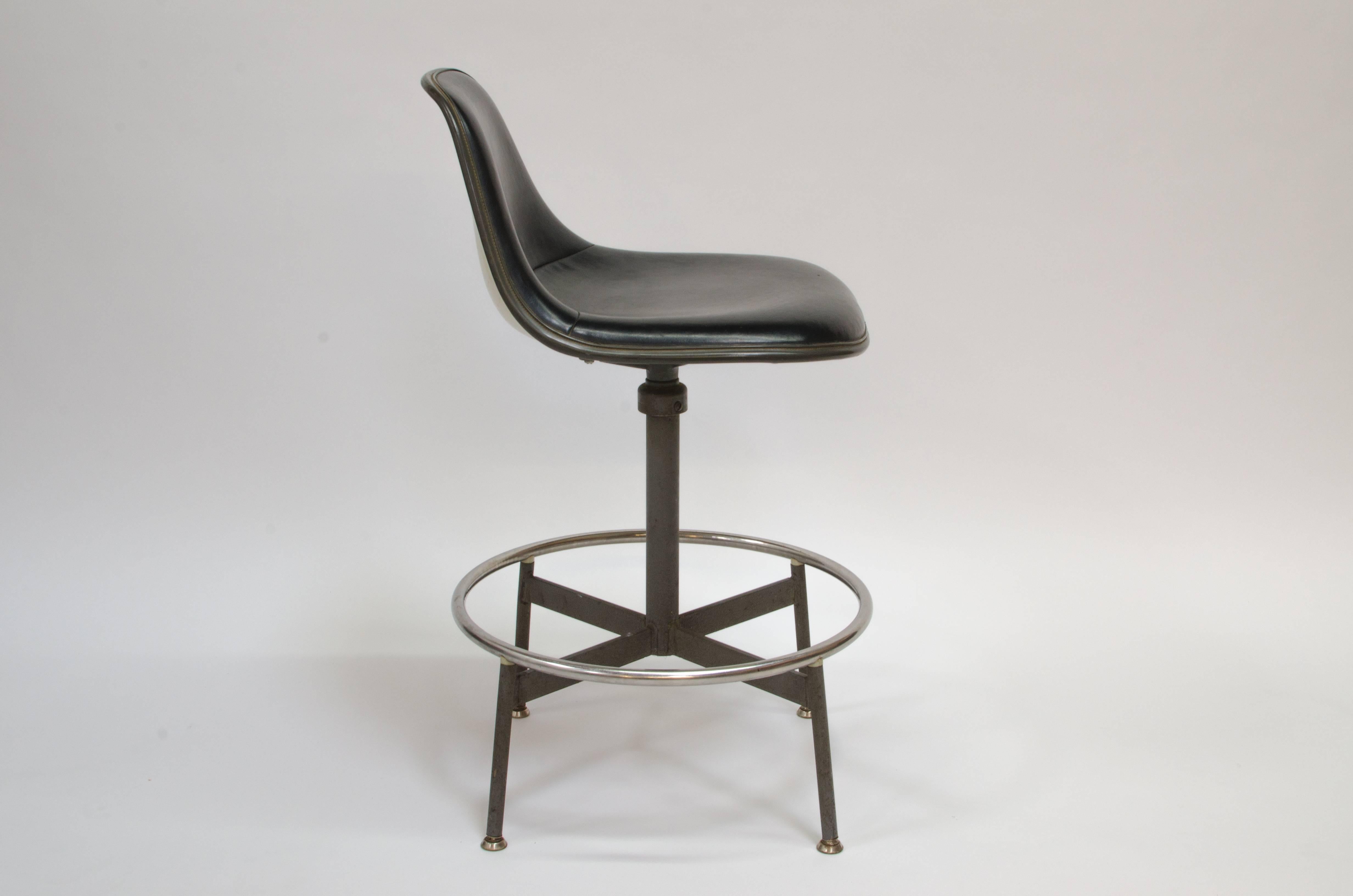 First generation drafting stool designed by Charles & Ray Eames for Herman Miller. Rarely seen combination features a short back parchment colored fiberglass shell with a black Naugahyde seat cover. The seat is height adjustable.