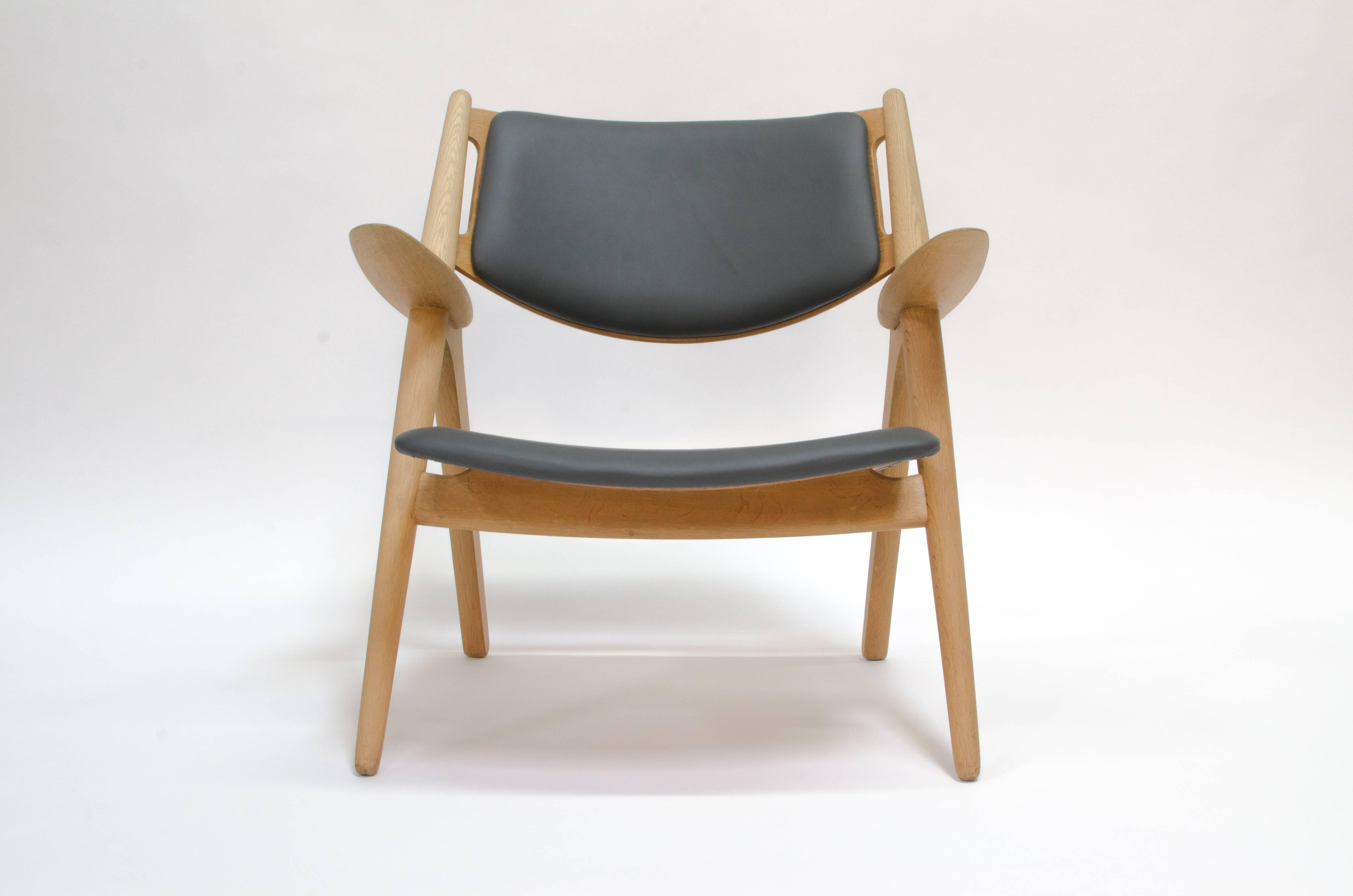 Offered is an early production Sawbuck lounge chair designed by Hans J. Wegner for Carl Hansen & Sons. This is an early production chair in excellent condition. It has been correctly reupholstered with Elmo (Sweden) leather, and the oak has the