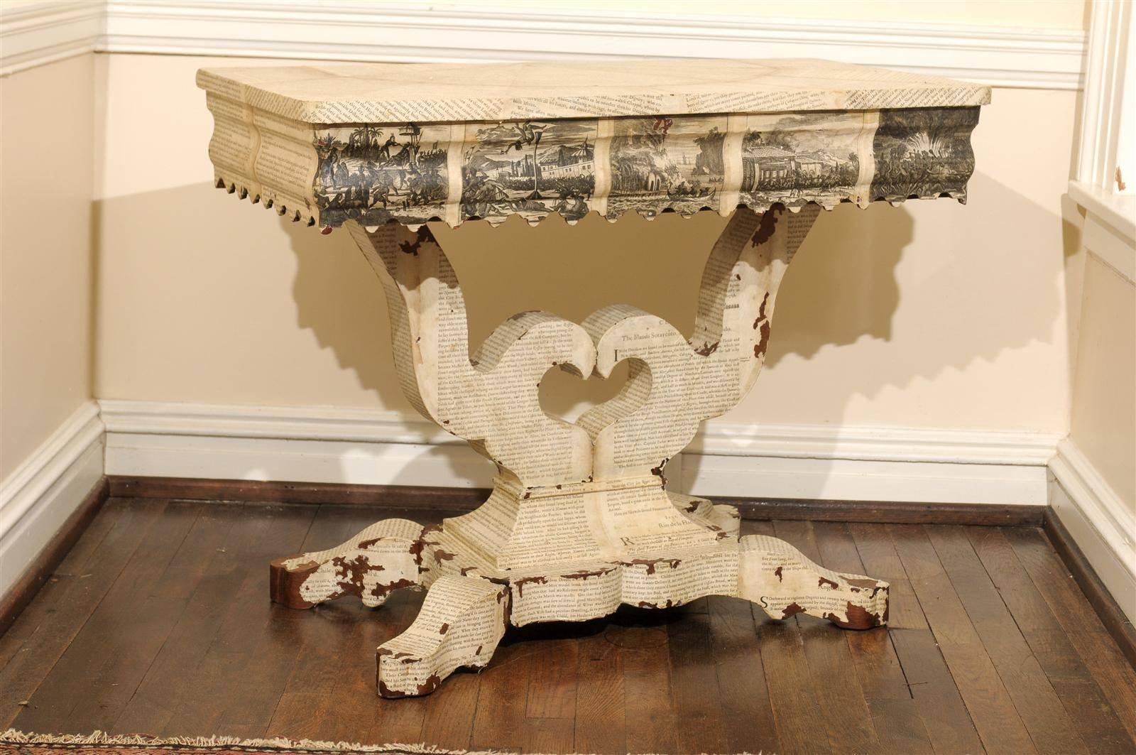 19th century American Empire console table decoupaged in antique texts about America. The pages on top are layed out in a demilune pattern and the frieze is covered in depictions of colonists and native Americans.