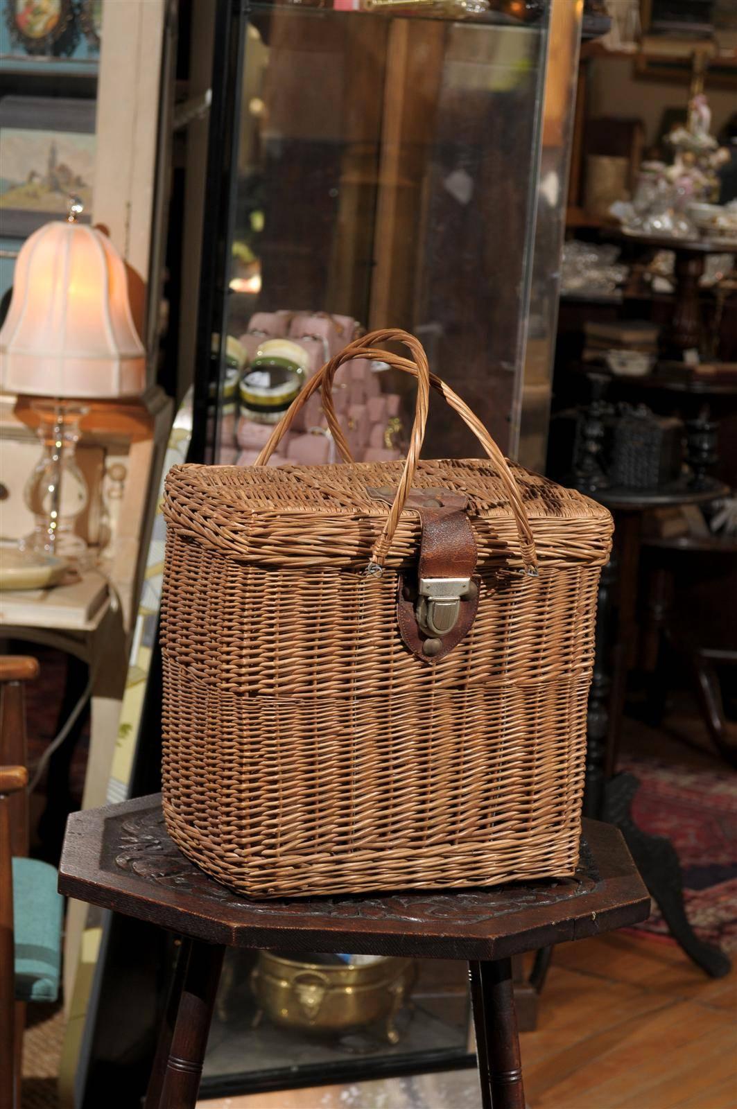 French wicker basket with a leather closure on the lid and a pair of woven handles.