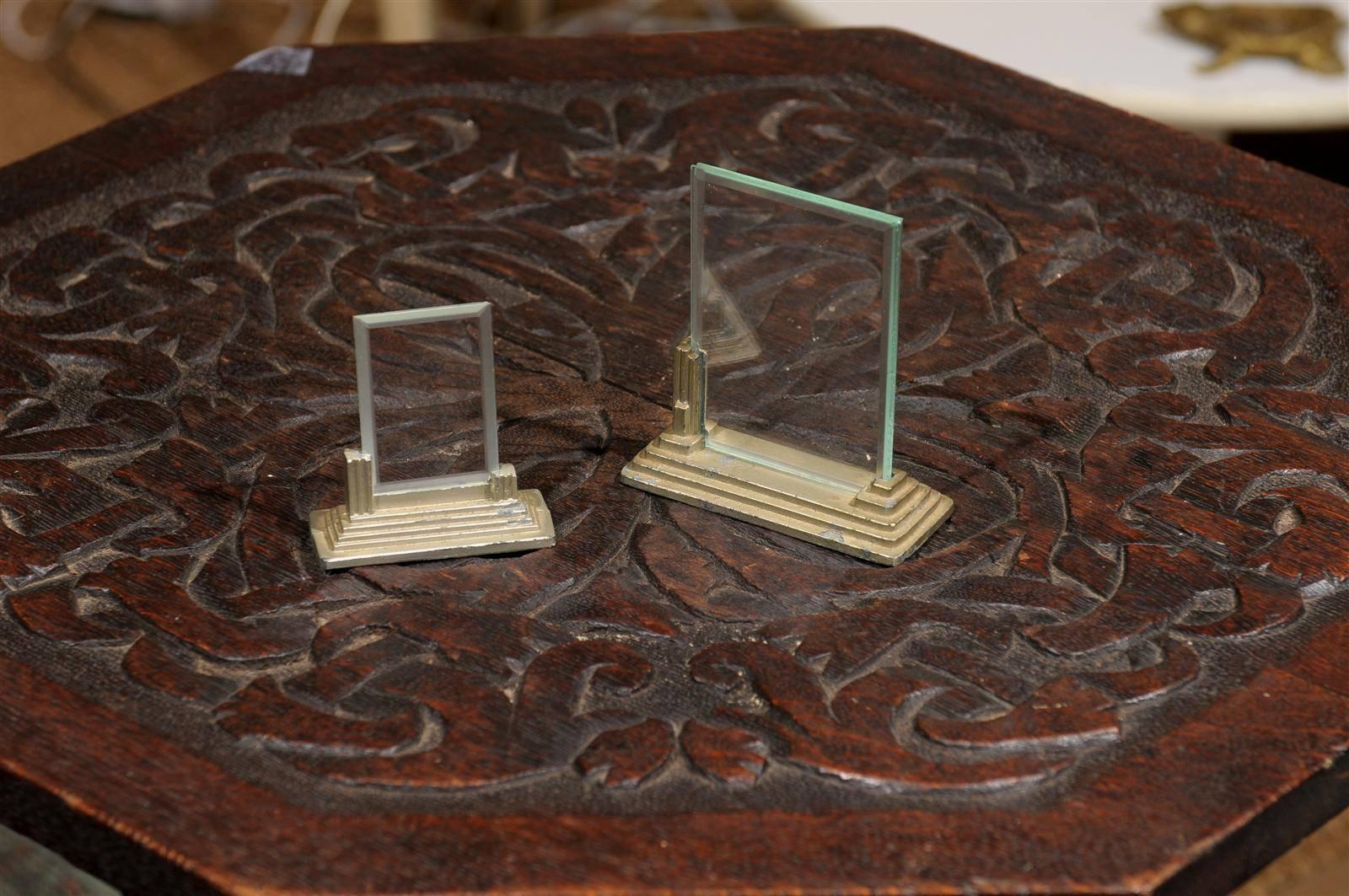 Early 20th century friendly pair of Art Deco period picture frames with removable beveled glass held by asymmetrical and tiered metal bases. The larger measures 3.75