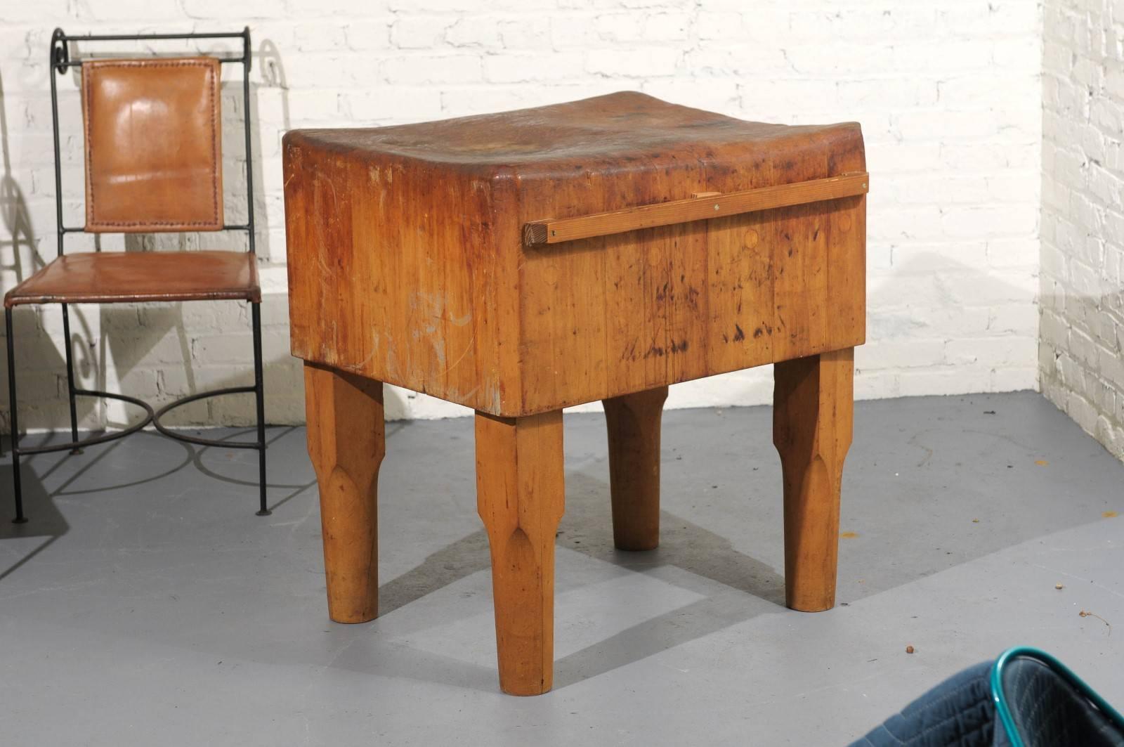 Early 20th century American butcher block table of maple with heavy wear and patina from use on the top. The table has a later added knife or towel rack on one side.