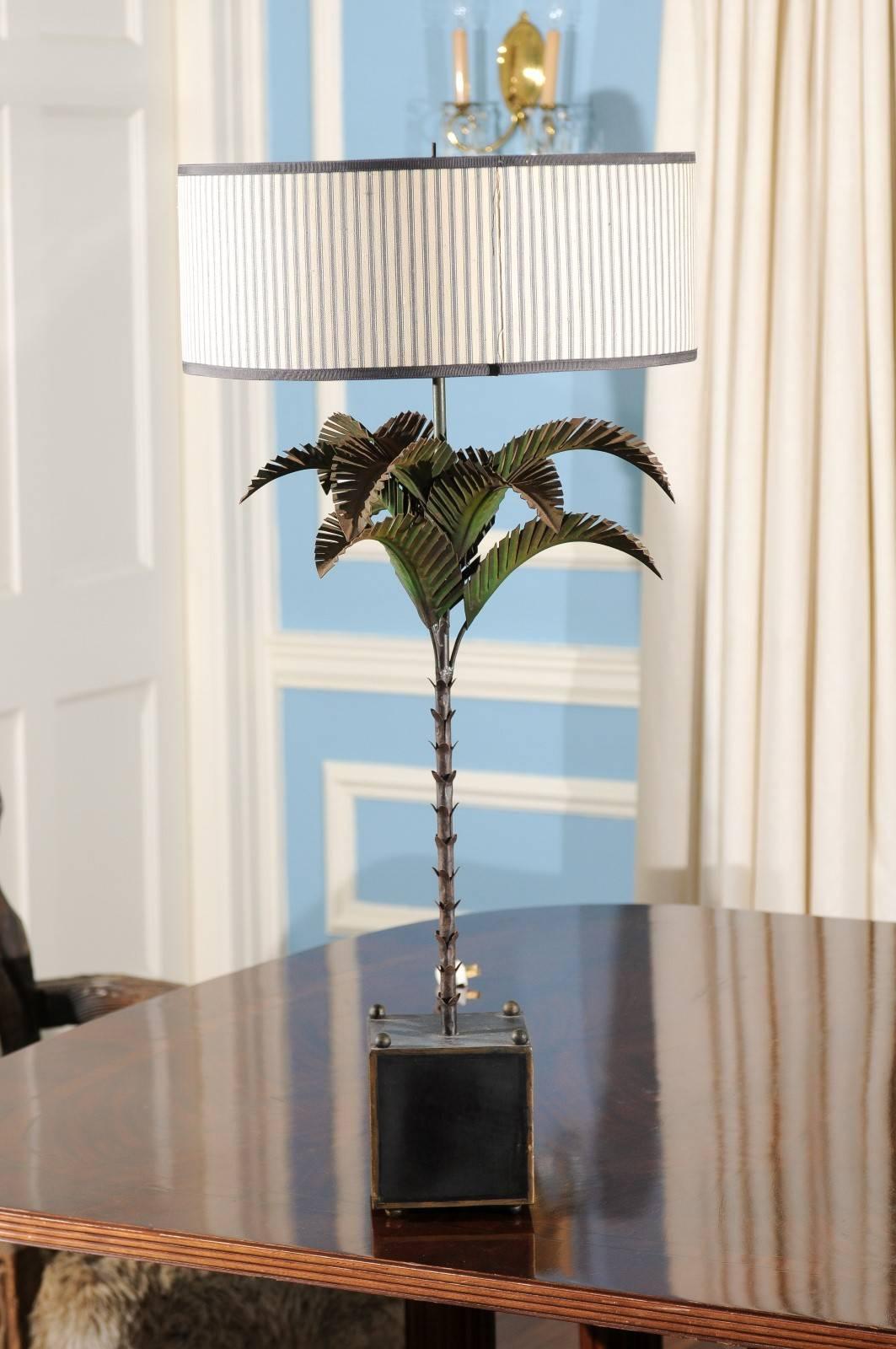 20th century, Italian palm tree table lamp made of tole and in a naturalistic form. The tree terminates into a black and gilt square tole box resembling a planter and is crowned by the original cylindrical barrel shade having a cream and gray