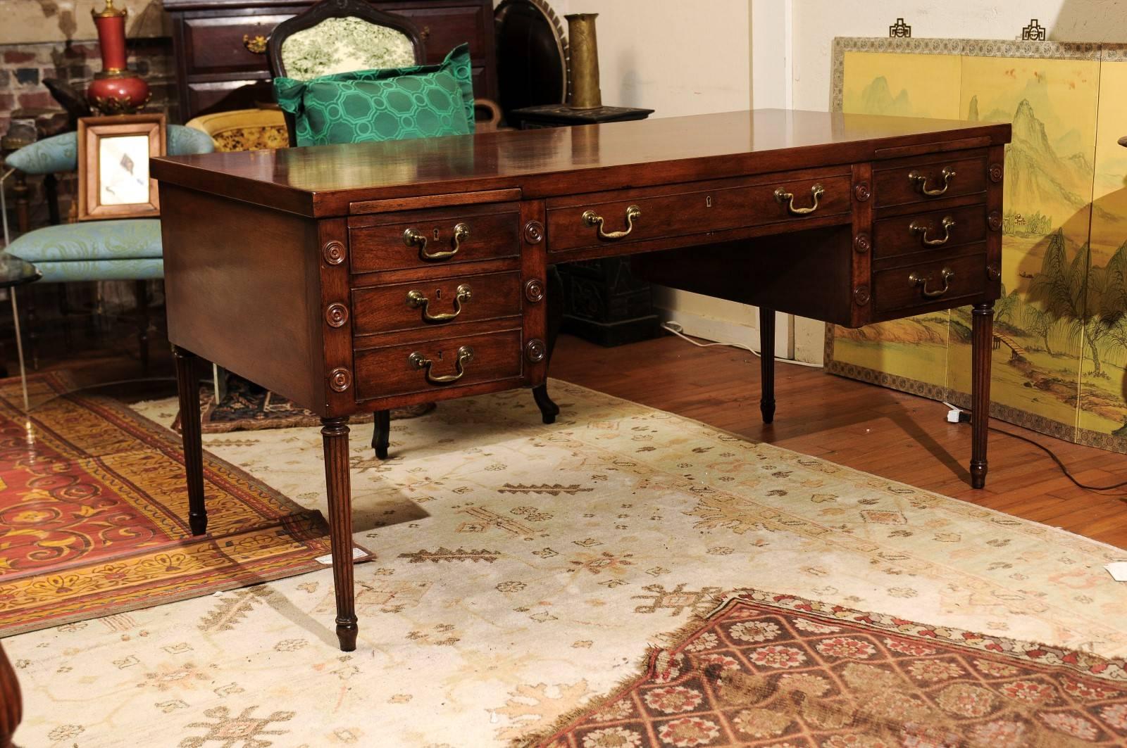 20th Century partners' desk of mahogany made in the Regency style and having a solid mahogany one board tabletop. The desk front has a wide center drawer (with working lock and key) flanked on each side by a wooden pull-out writing surface above one