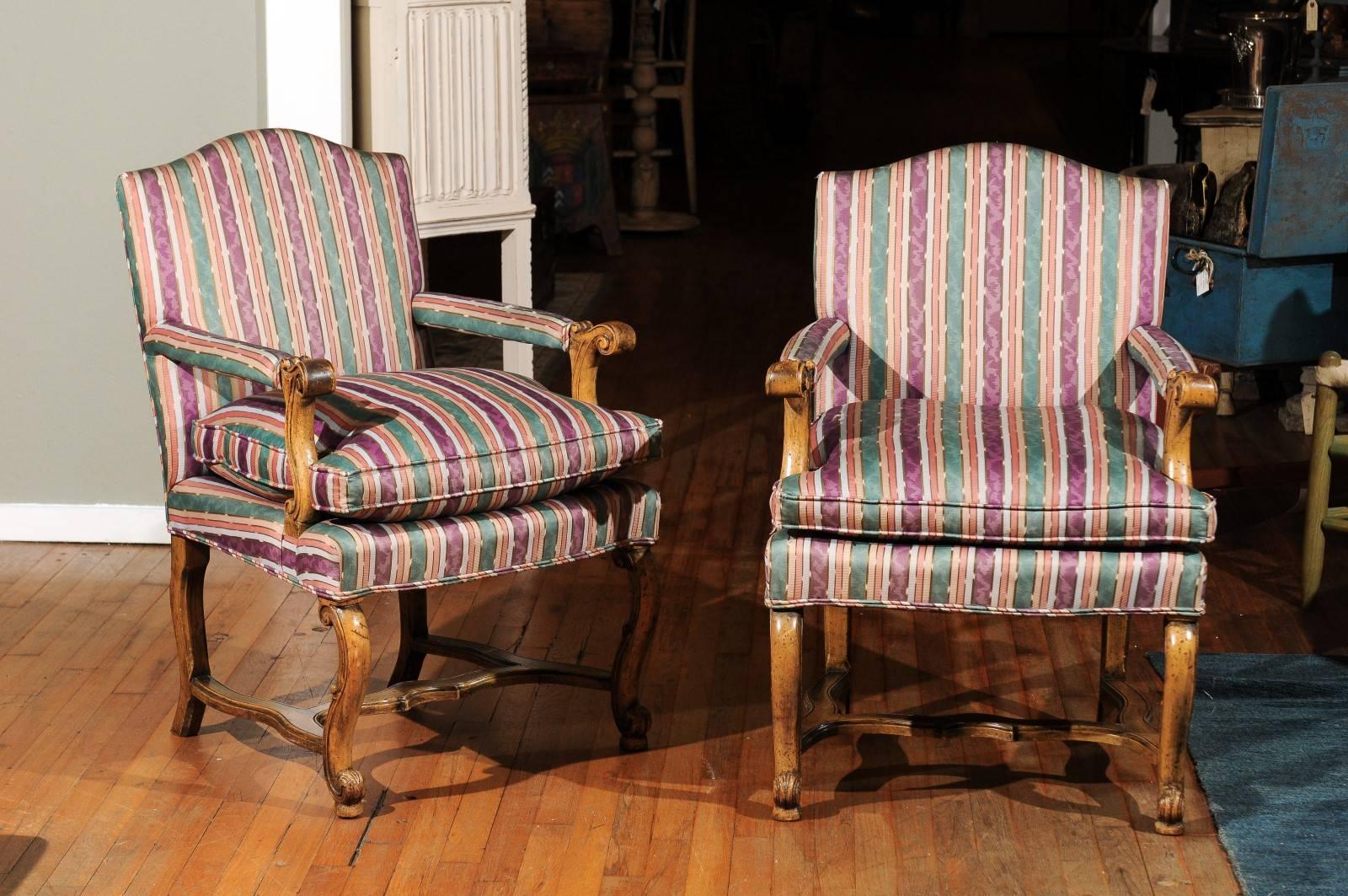 Pair of 20th century Italian bergère chairs having an upholstered back and seat and custom loose down removable cushion. The beechwood finish wooden frames have scrolling arms and legs and shaped H-stretchers.