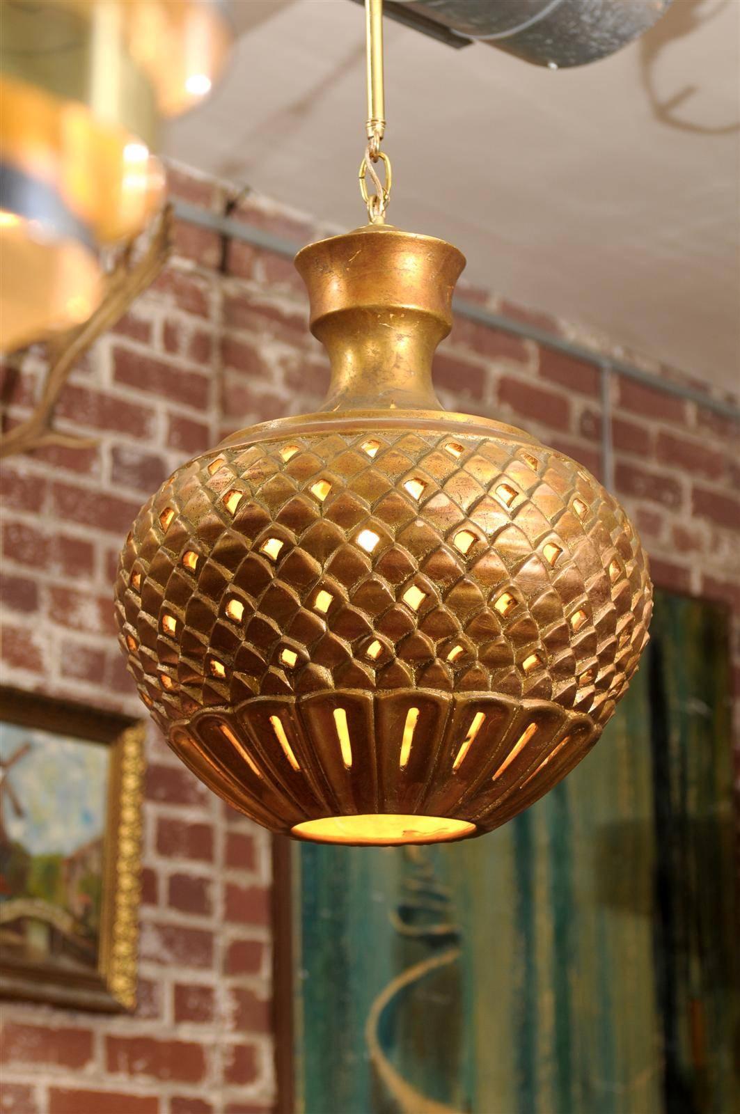 Midcentury hanging lantern or globe in the Hollywood Regency style, made of plaster with raised and pierced designs, and finished in gilt.  Suspended by a brass bar and ceiling cap (included in measurements below.)  