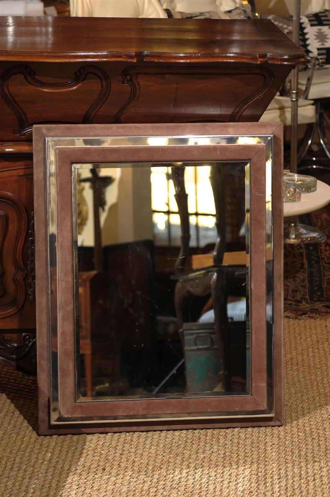 Art Deco period dimensional mirror made of a back suede box frame with a chrome frame layered above. The top panel is another suede frame holding an inset piece of beveled mirror glass.