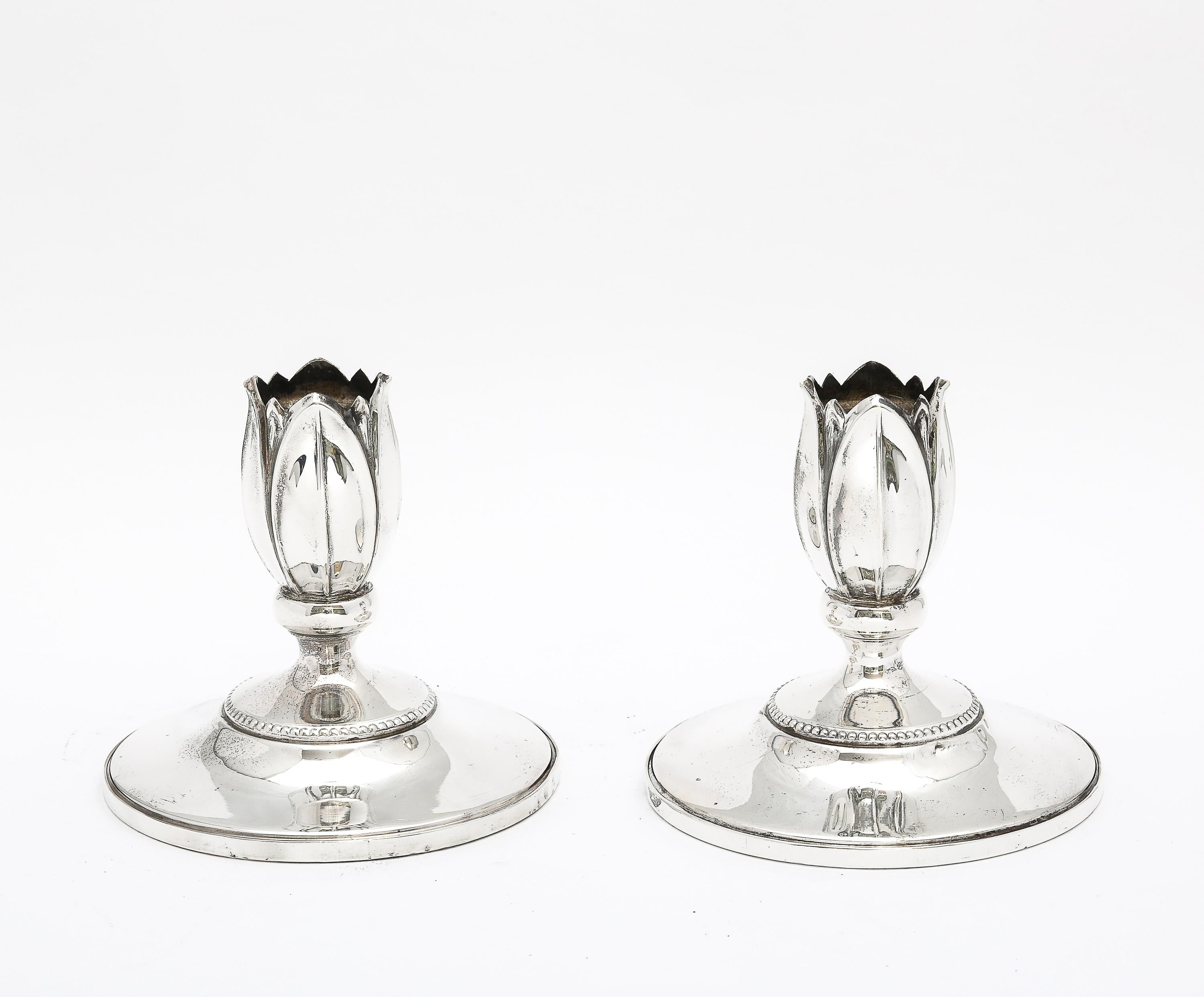 Coppia di candelieri in argento sterling in stile Art Nouveau, Fisher Silversmiths, Jersey City, New Jersey,  Ca. 1935. Con un design bello e grazioso, ogni candeliere sembra un fiore che emerge dalla sua base. Ogni candeliere misura quasi 4 pollici