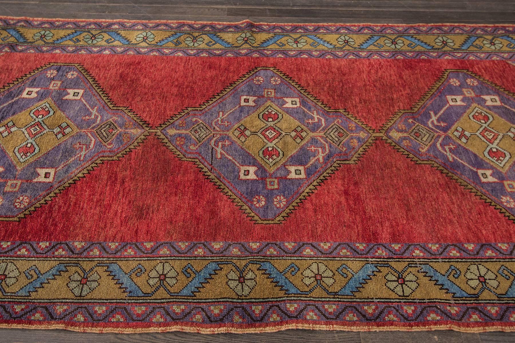 Vintage Hand-knotted rug with a geometric and medallion design on a red field with green borders. 

This rug has magnificent detailing and would be perfect for any room.