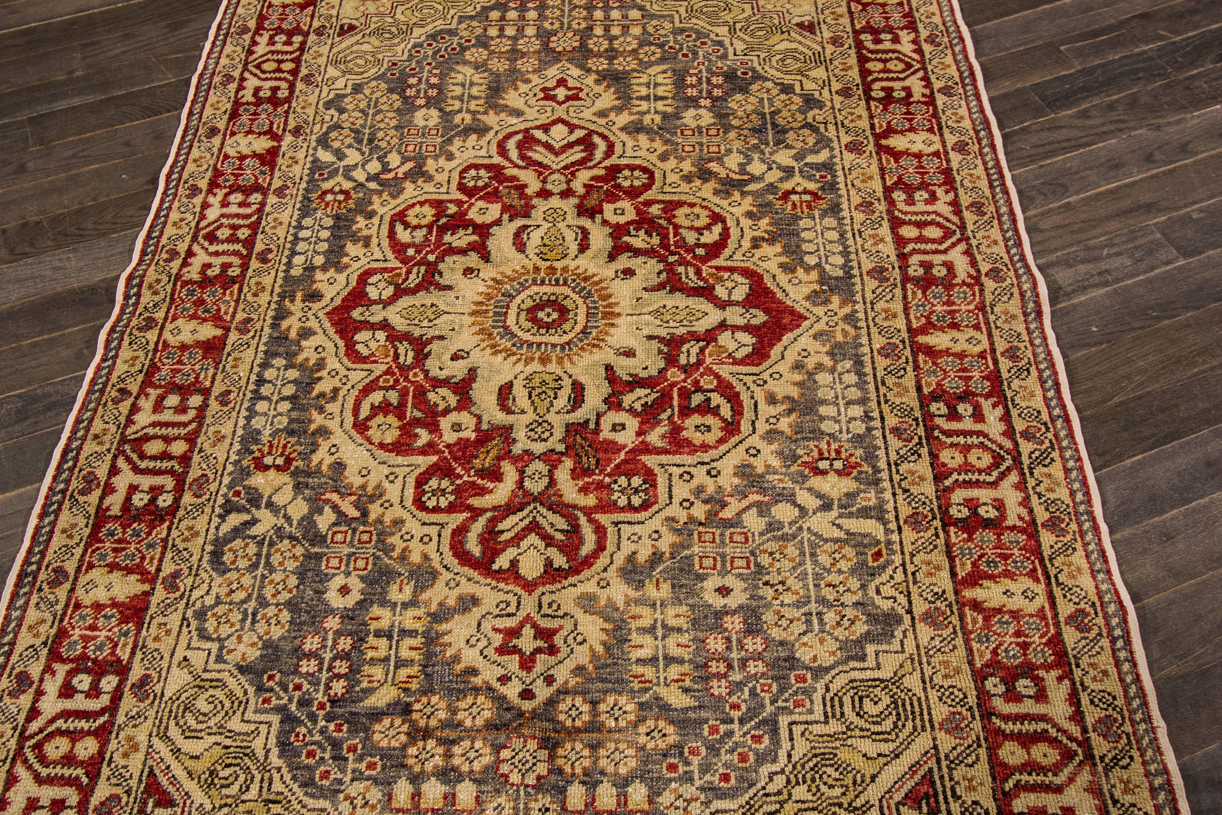 Vintage hand-knotted rug with a medallion design on a gray field with red borders.

This rug has magnificent detailing and would be perfect for any room. Measures: 4'4