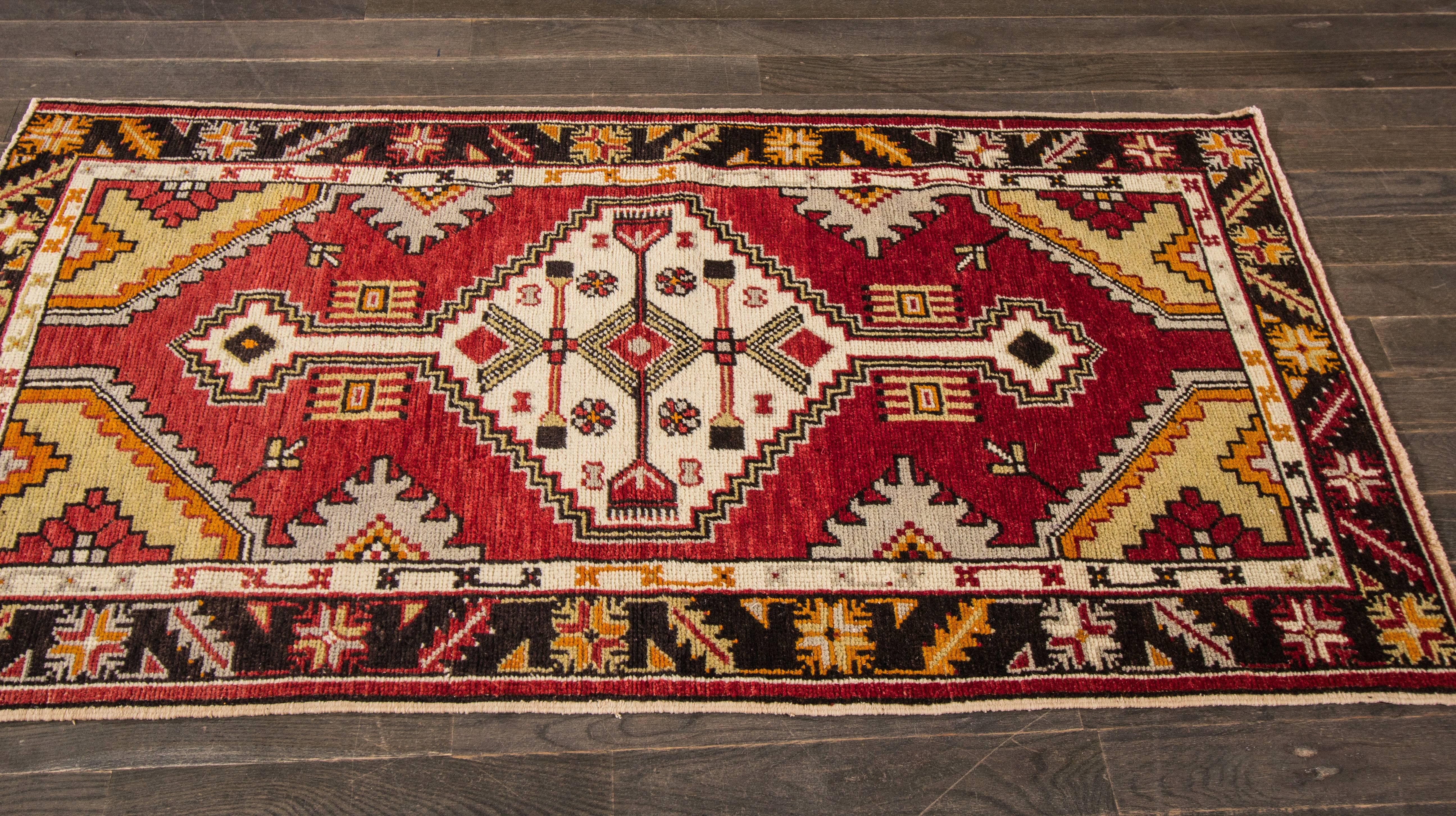 Handgeknüpfter Teppich mit geometrischem und Medaillon-Muster auf rotem Feld mit schwarzer Umrandung. 

Dieser Teppich mit seinen prächtigen Details eignet sich für jeden Raum. Maße: 2'9