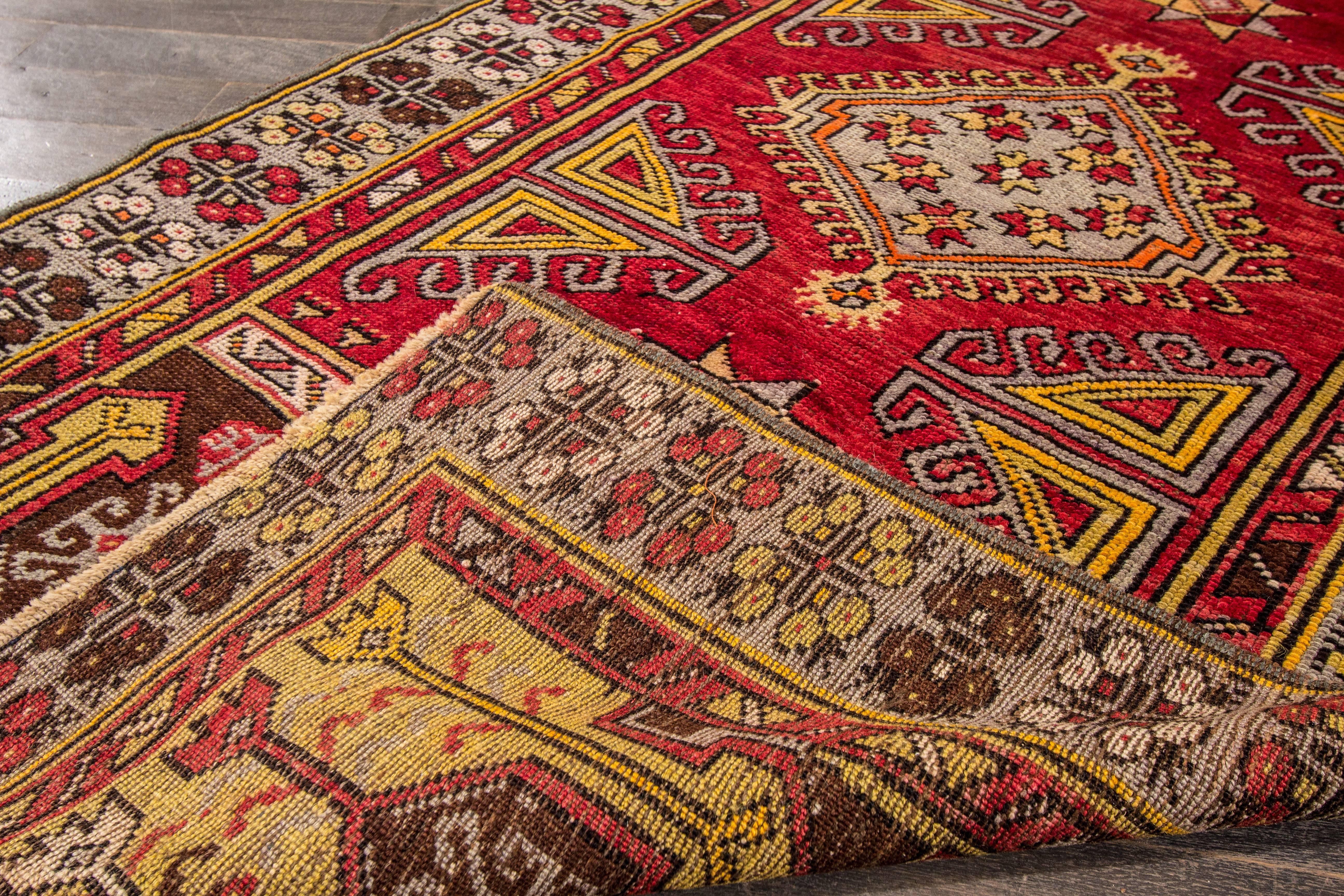 Hand knotted rug with a geometric and medallion design on a red field with gray borders. Measures: 3'2' x 5'9
