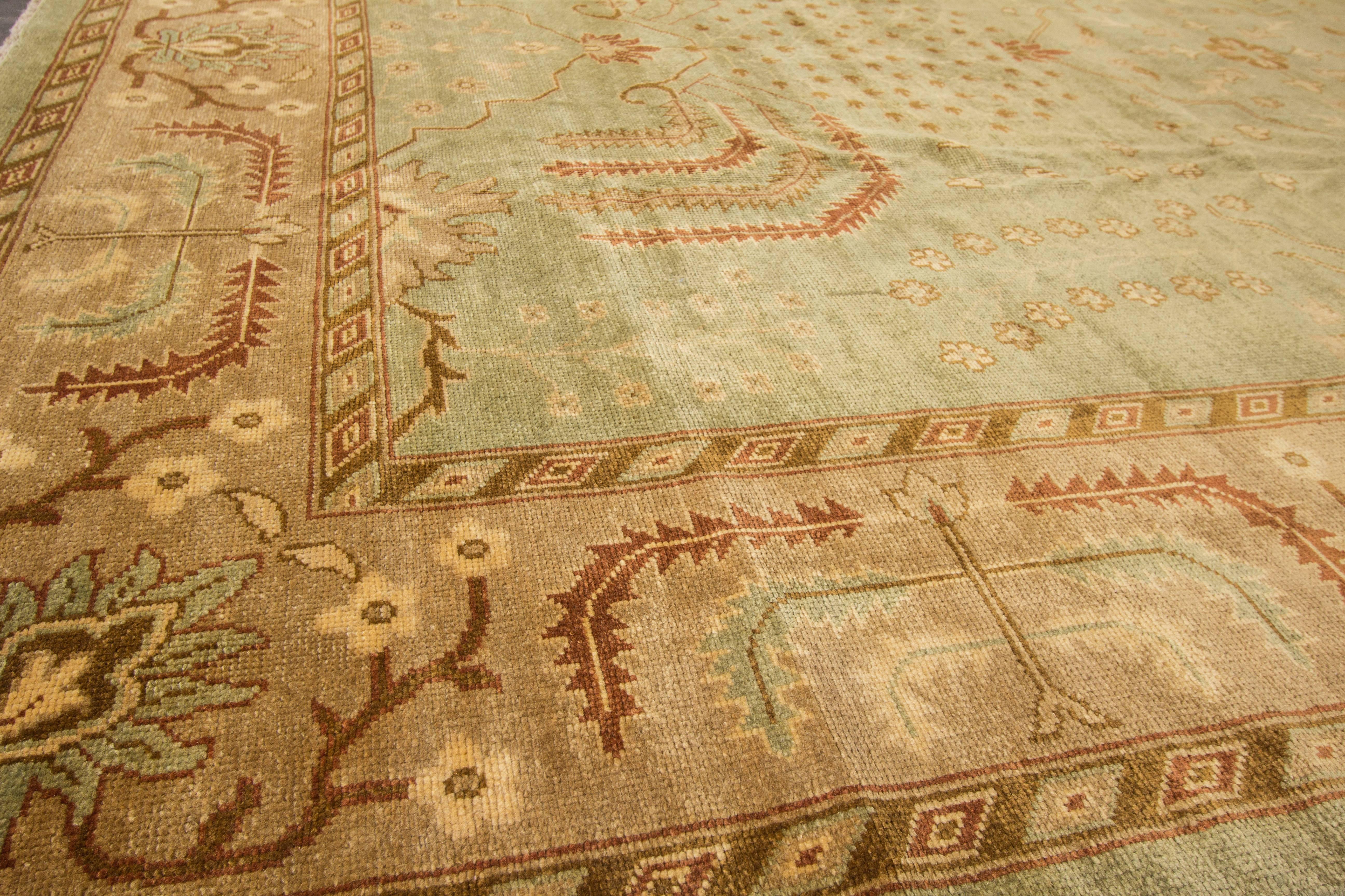 Hand-knotted rug with a floral and medallion design on a green field with beige borders. Measures: 9'10