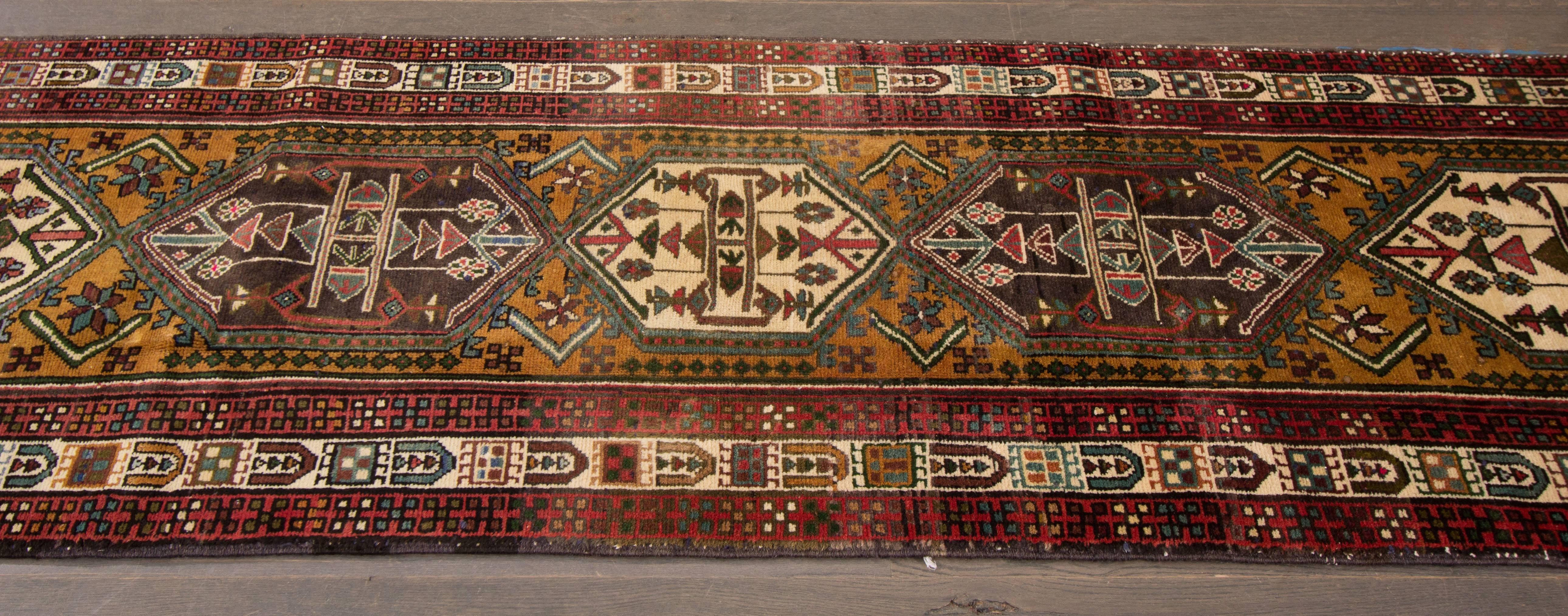 Heriz carpets are beloved for their versatility. Their geometry complements modern furnishings and their warm colors and artistic depth enhance antiques of all kinds. This 20th century Heriz runner features five beautiful stylized geometric