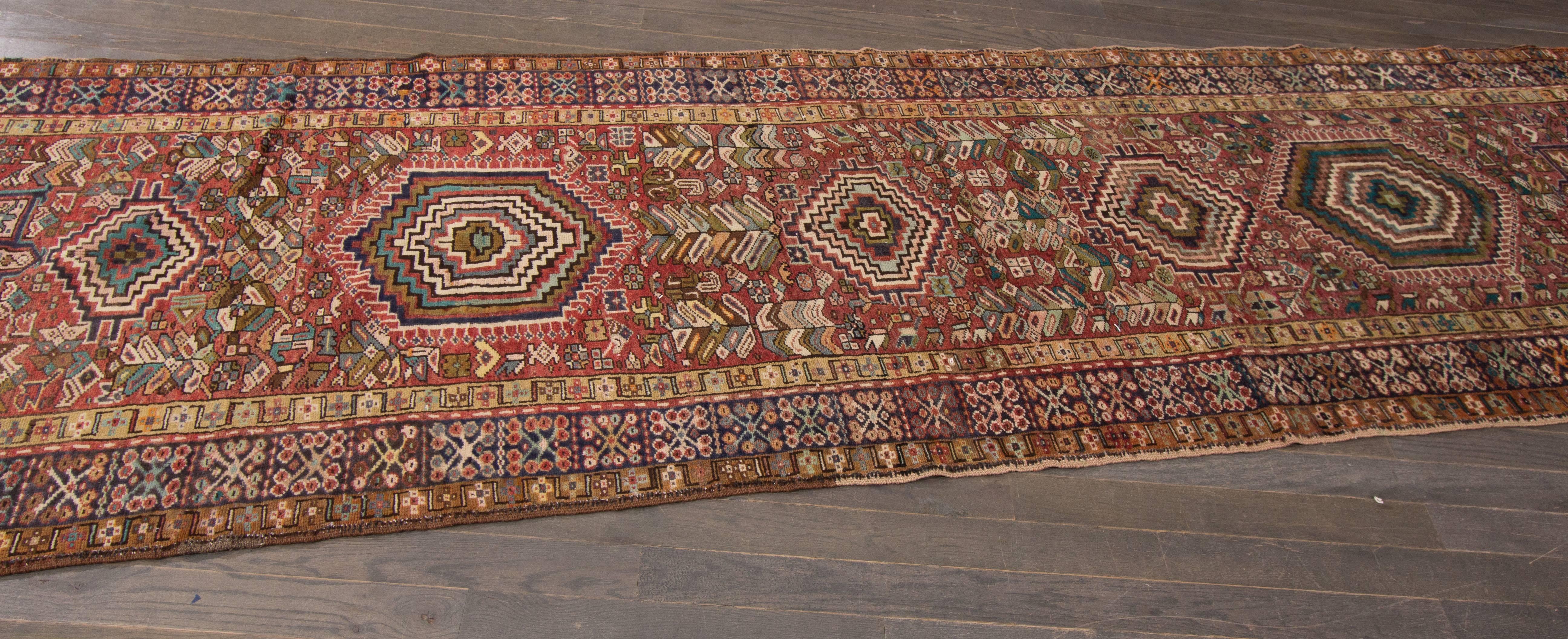 Heriz carpets are beloved for their versatility. Their geometry complements modern furnishings and their warm colors and artistic depth enhance antiques of all kinds. This 20th century Heriz runner features seven beautiful stylized geometric