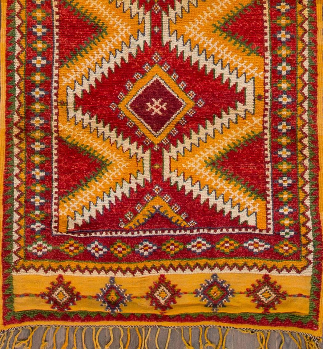 Vintage 1930s Moroccan carpet with a red field, orange and green geometric design, measure: 4.04 x 11.