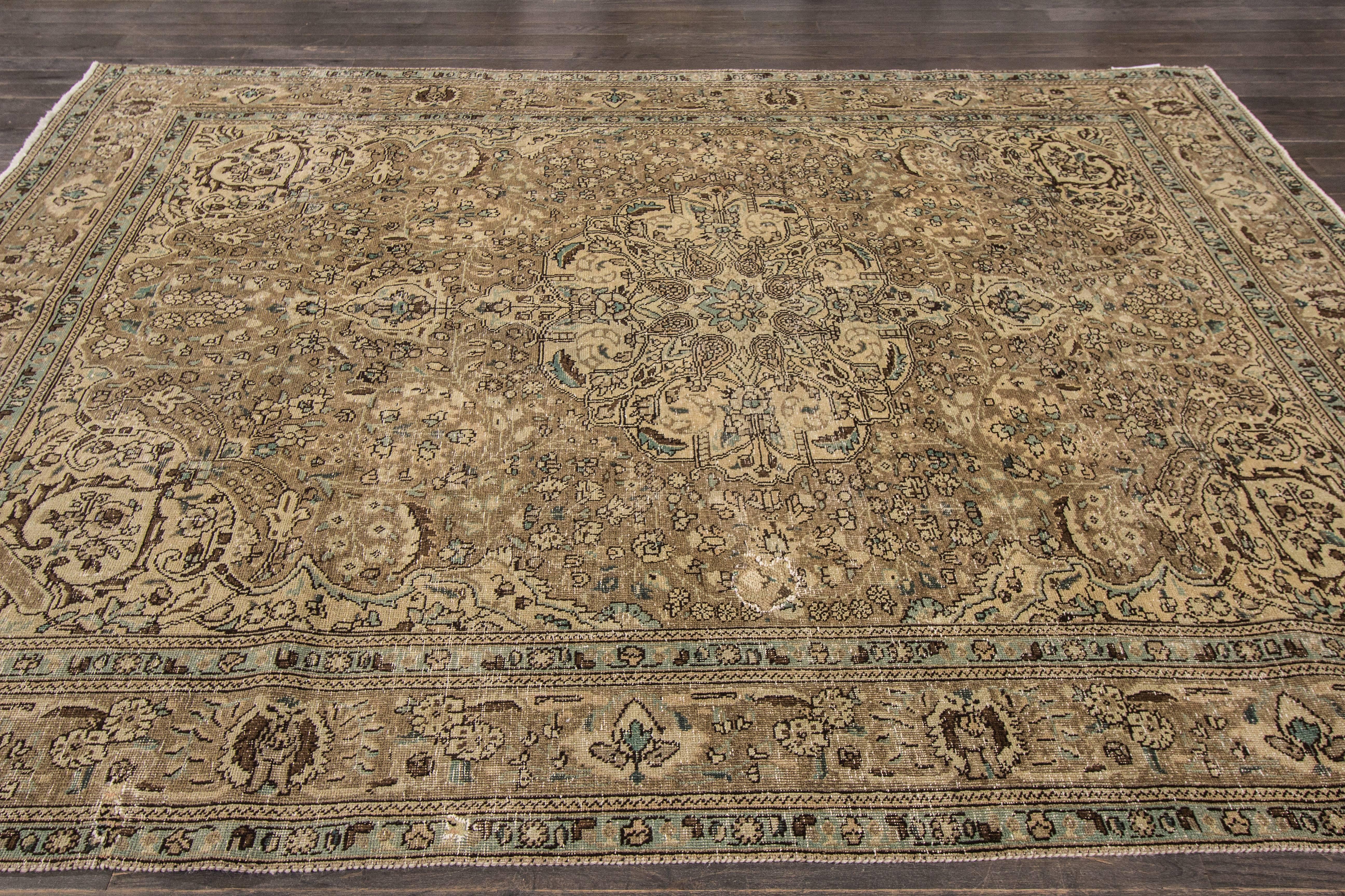 Measures: 7'.2 x 9'.7
A hand-knotted antique Persian Tabriz rug with a floral design on a beige field. Accents of brown and green throughout the piece.