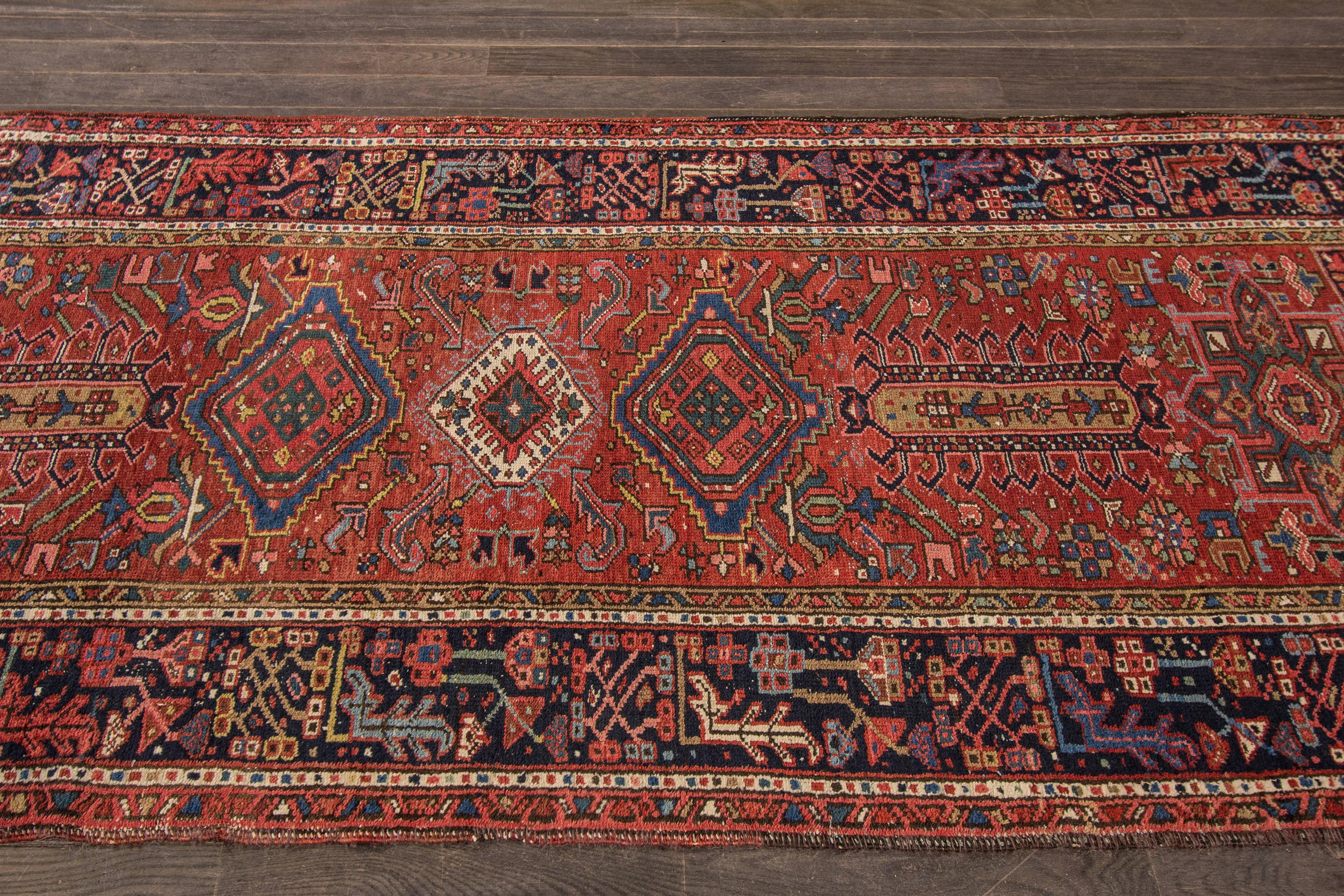 Measures: 3'.7 x 13'.3
A hand-knotted antique Persian Heriz rug with a geometric floral design on a red field. Accents of black, blue and ivory throughout the piece.