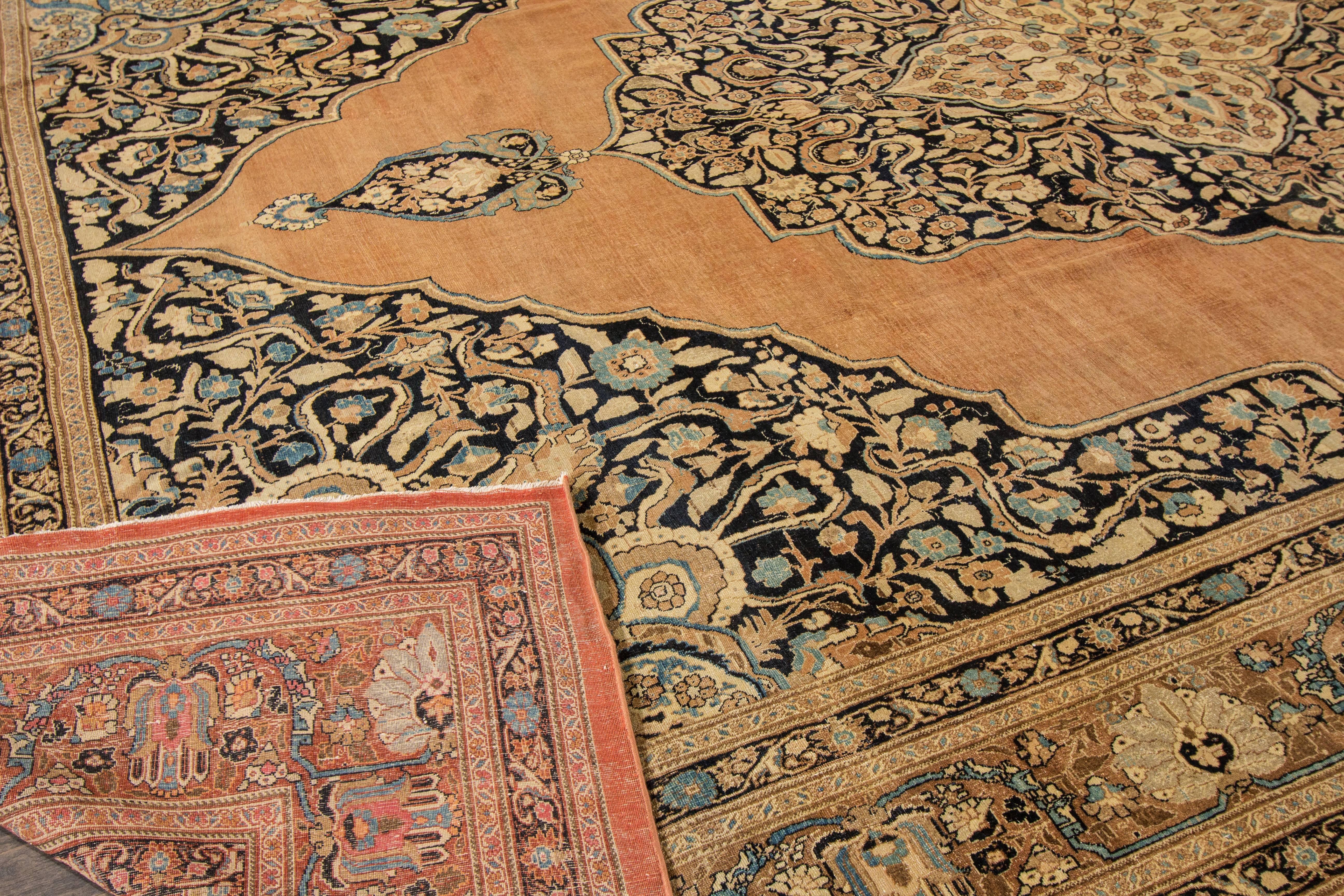 A hand-knotted antique Tabriz rug with a floral medallion design on a beige field. Accents of black, brown and blue throughout the piece. The size of this piece is 11' x 16'.9.