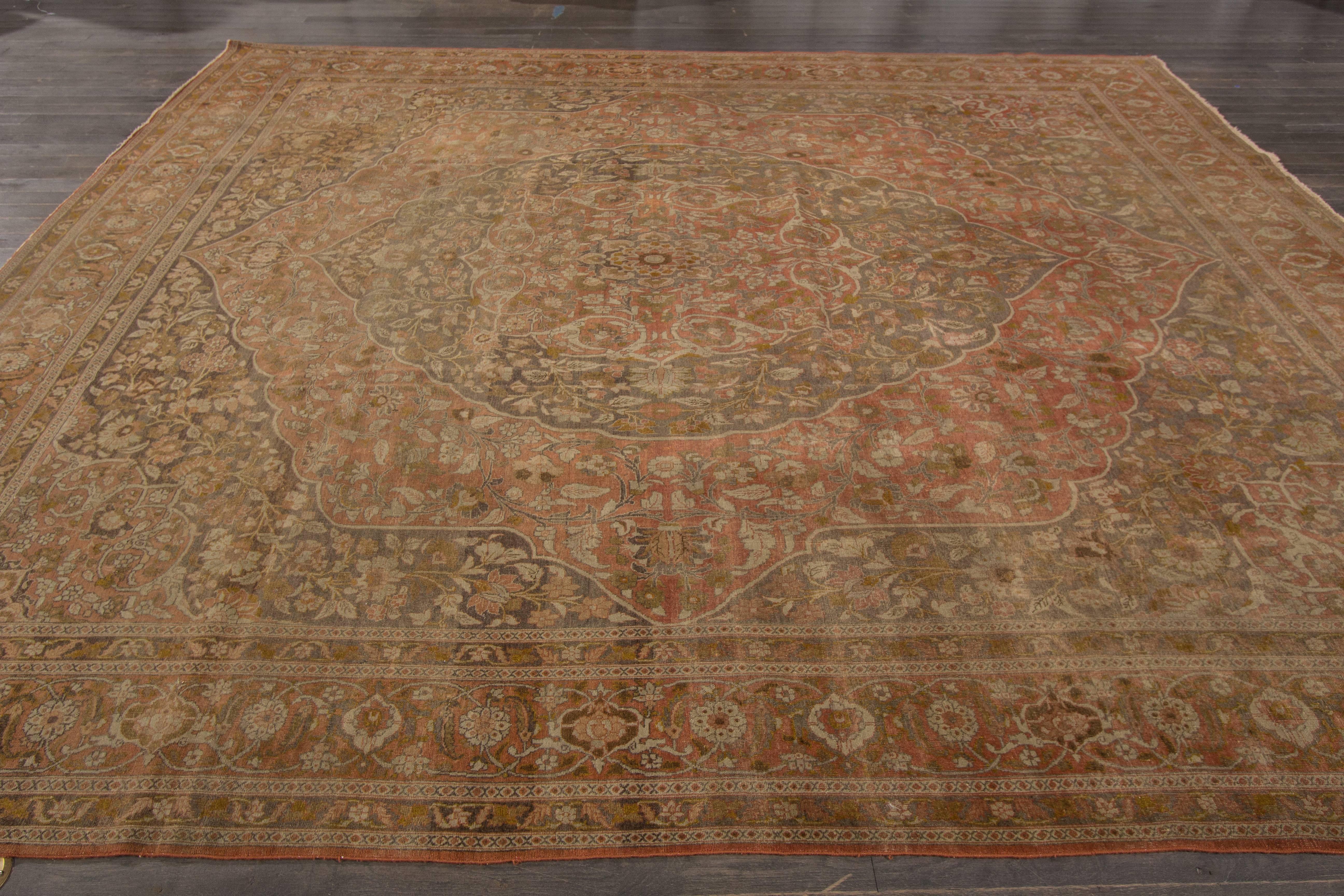 A hand-knotted antique Tabriz rug with a floral design on a brown field. Accents of beige, green and red throughout the piece. The size of this piece is 10'.7 x 12'.8.