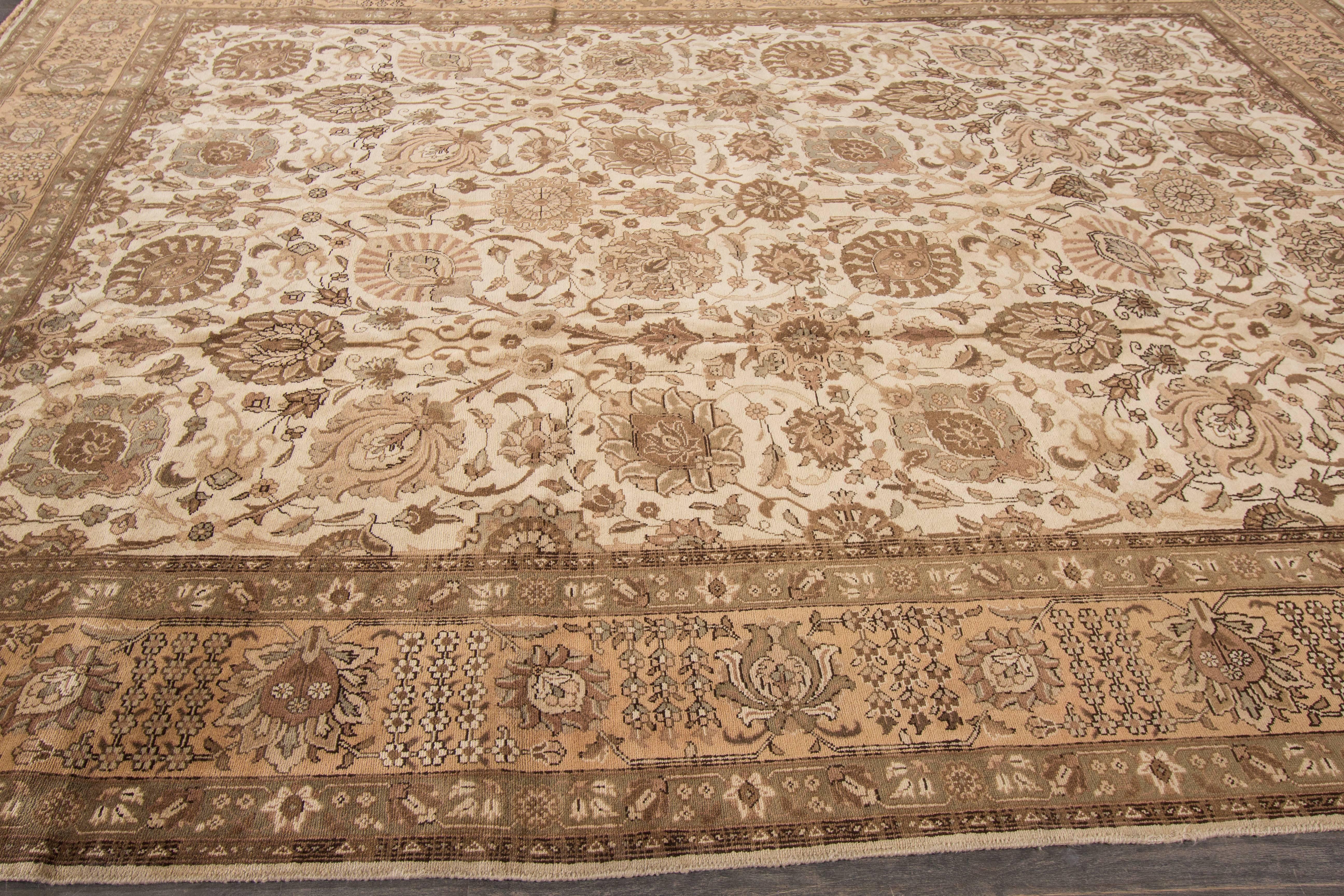 A hand-knotted antique Tabriz rug with a floral design on a beige field. Accents of brown and ivory throughout. The size of this piece is 9'.8 x 12'.9.