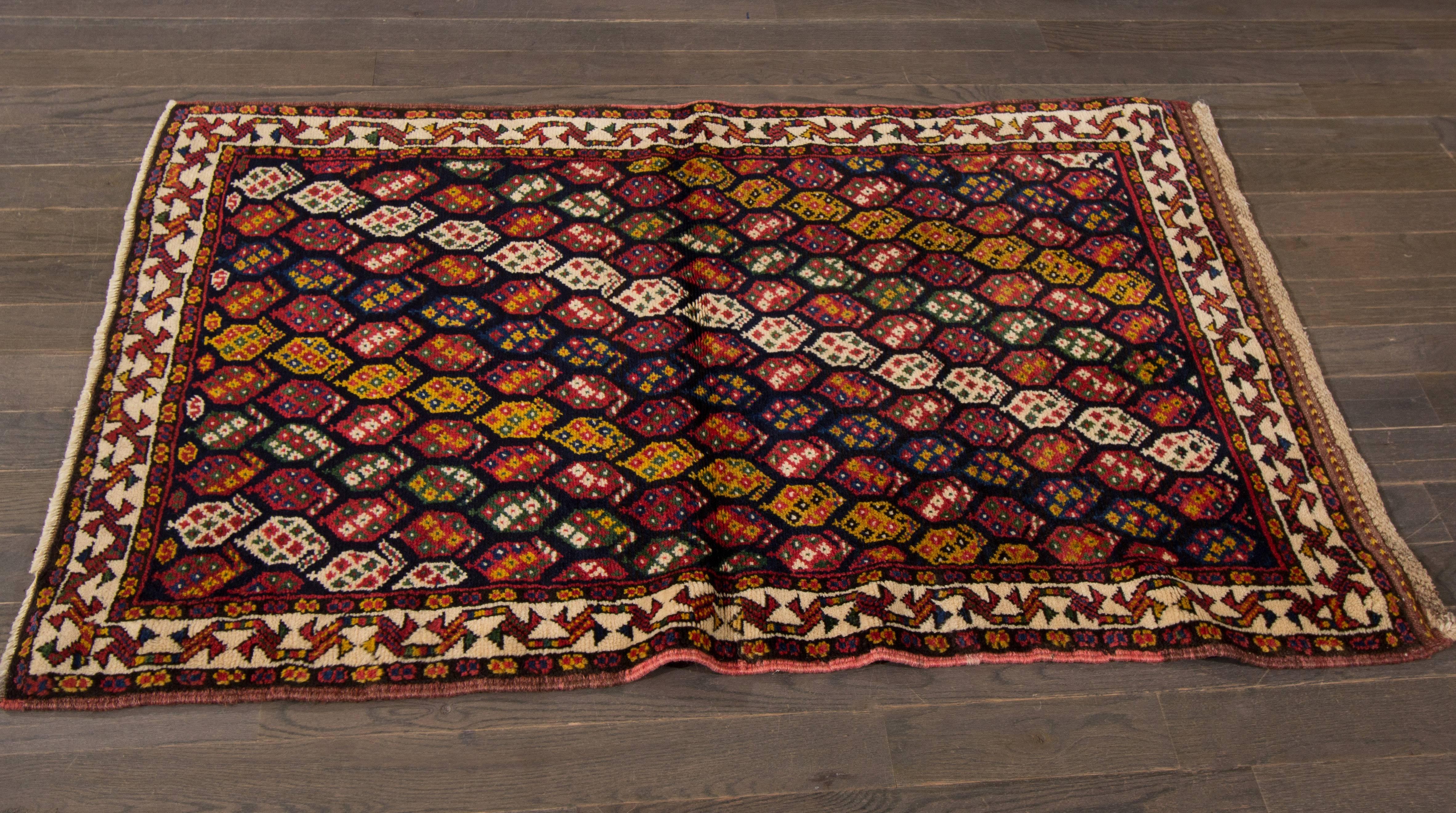 A hand-knotted Shiraz rug with a geometric pattern design on a black field. Accents of red, orange, green and ivory throughout the piece. This rug measures 3' x 4'.9.