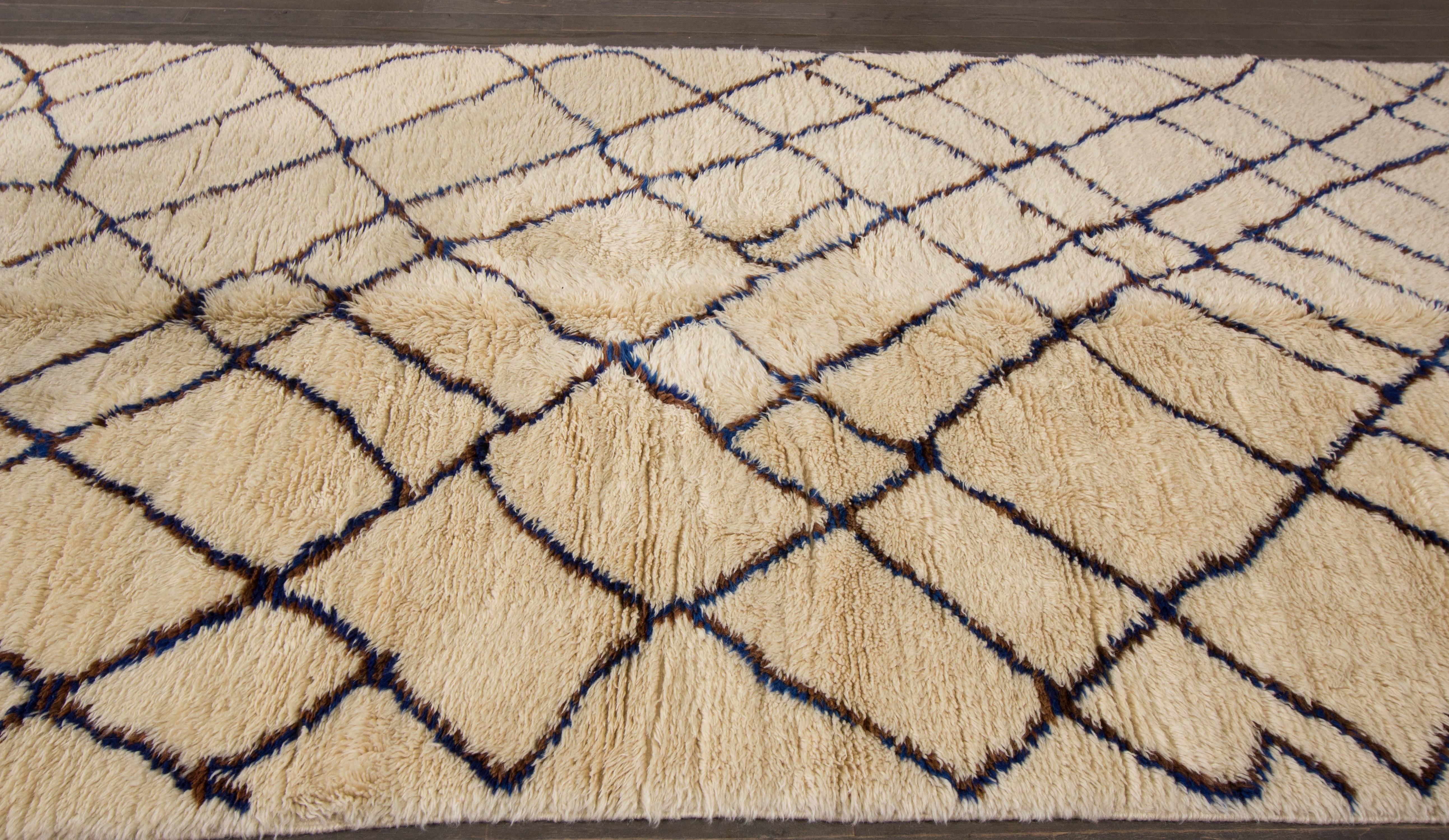 A hand-knotted Moroccan rug with a geometric design on an ivory field. Accents of brown and beige throughout the piece. 

This rug measures 6'.1
