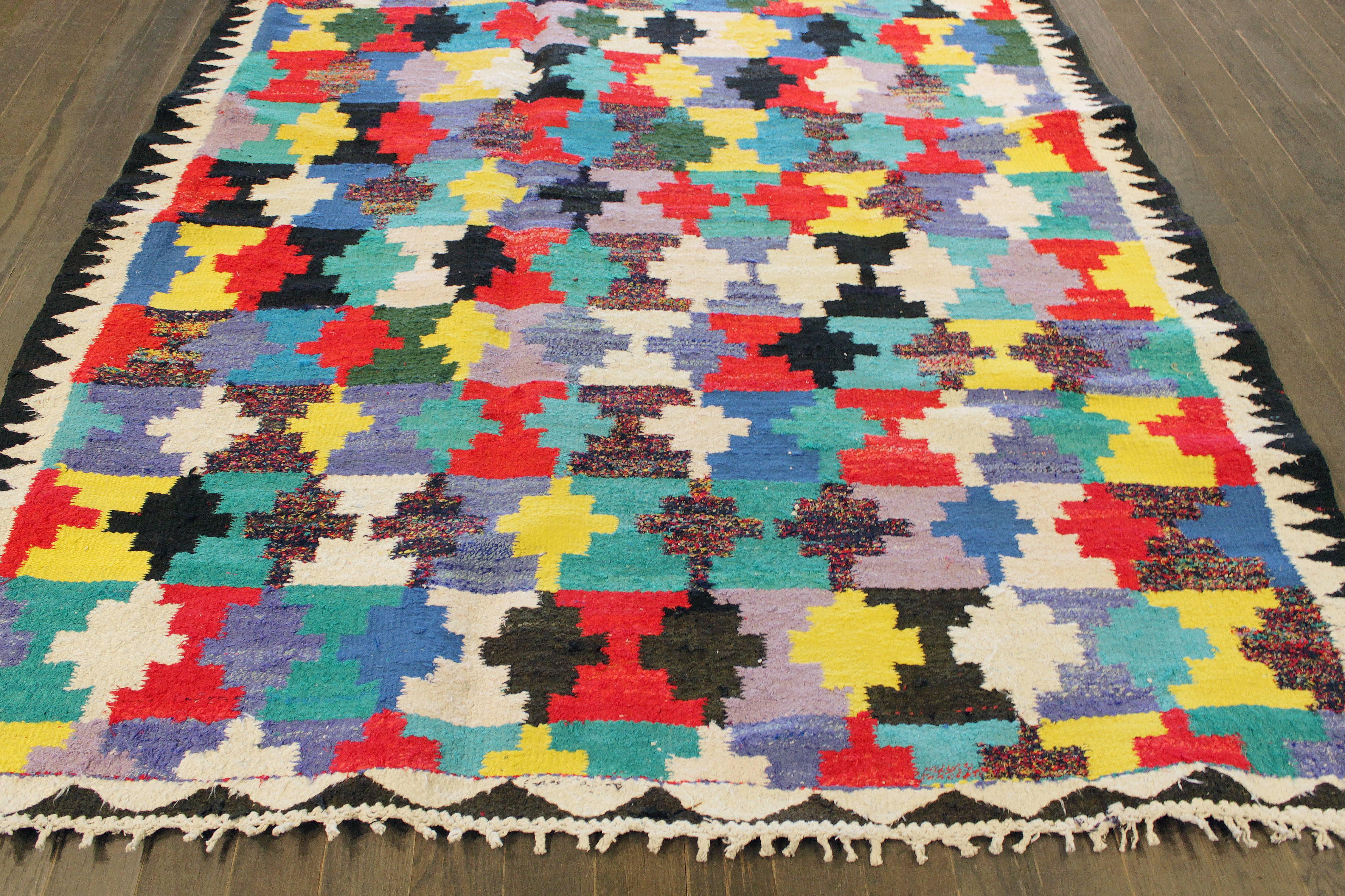 Ein handgeknüpfter Kelim-Teppich mit einem kunstvollen Muster auf einem mehrfarbigen Feld. Rote, blaue, schwarze und gelbe Akzente im gesamten Stück. Dieser Teppich misst 5'.2 x 11'.5.