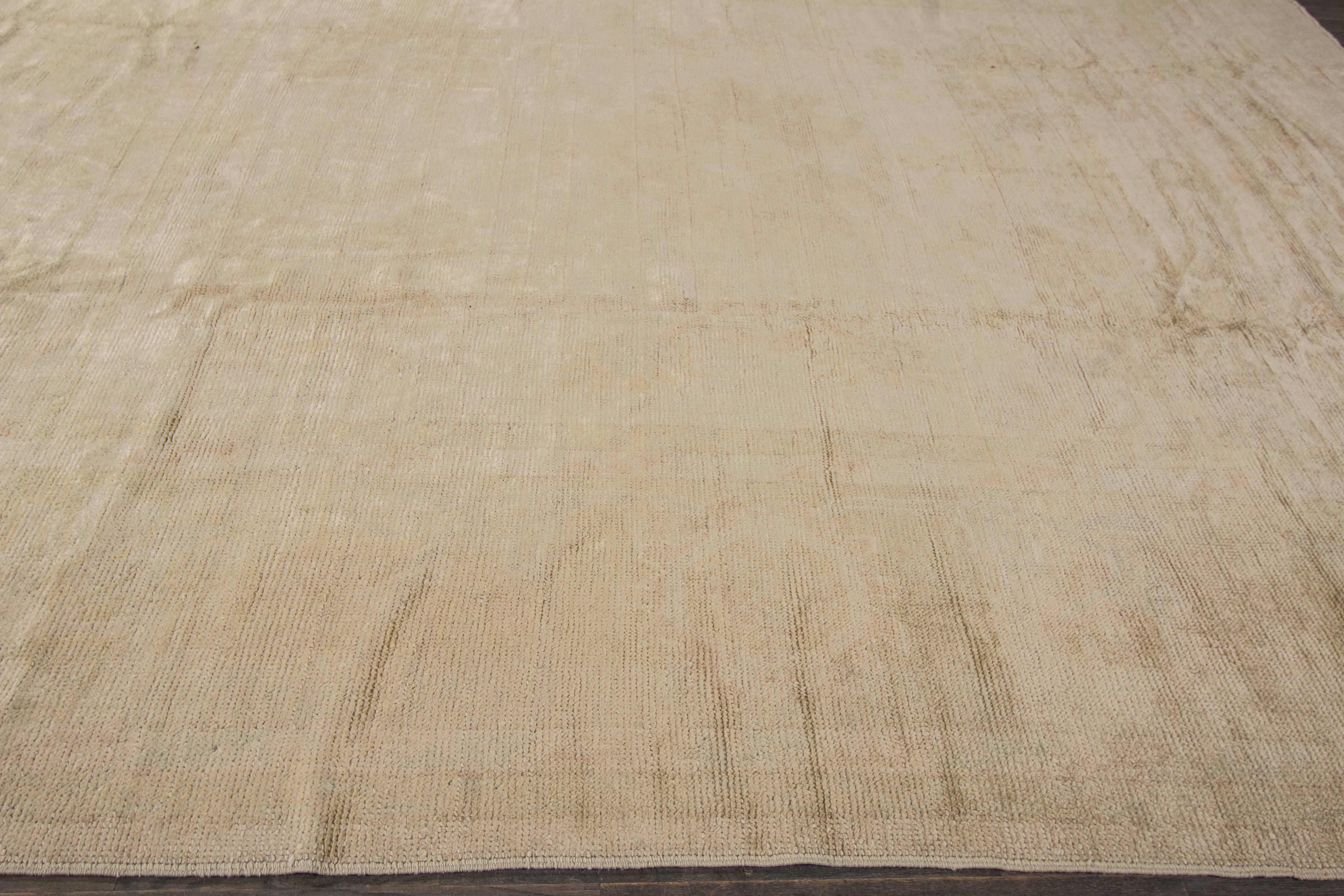 A hand-knotted Turkish Oushak rug with an all-over design on a beige field. Accents of ivory and brown throughout the piece. This rug measures 10'.9 x 12'.5.
