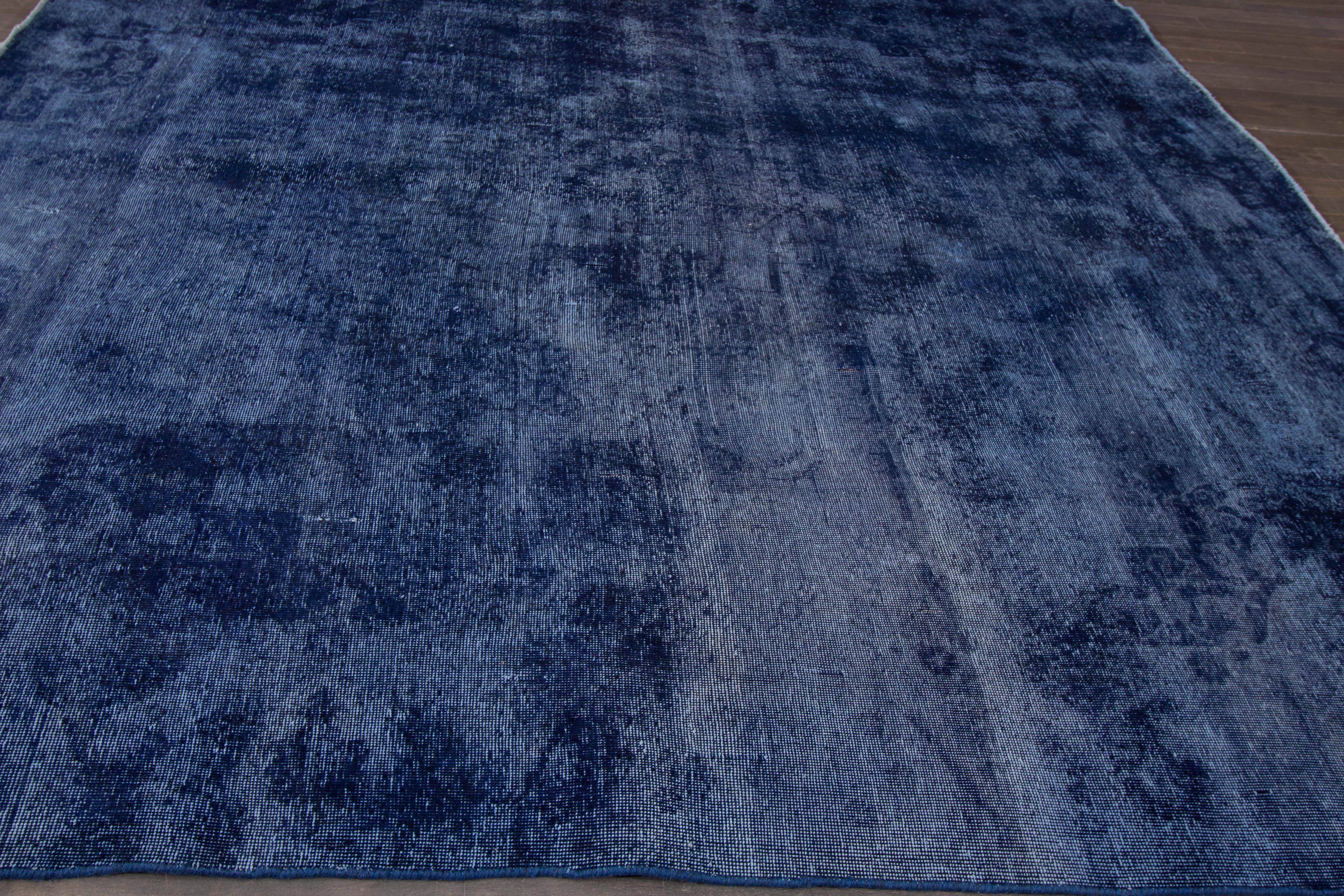 A hand-knotted square Overdyed rug with an all-over design on a blue field. Accents of different shades of blue throughout the piece. This rug measures 9'.5 x 9'.5.