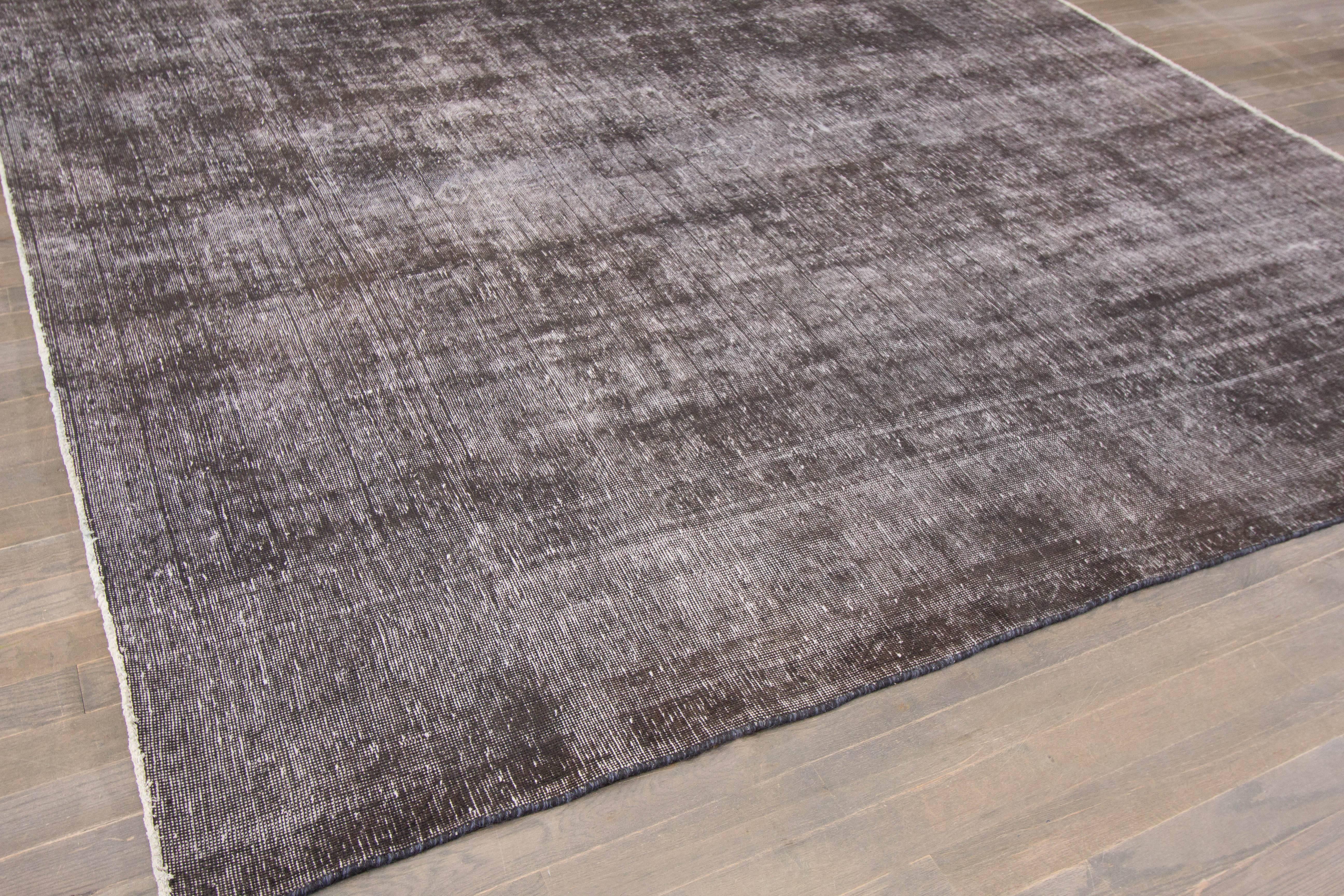 A hand-knotted square Overdyed rug with an all-over design on a grey field. Accents of brown and ivory throughout the piece. This rug measures 9'.4 x 9'.6.