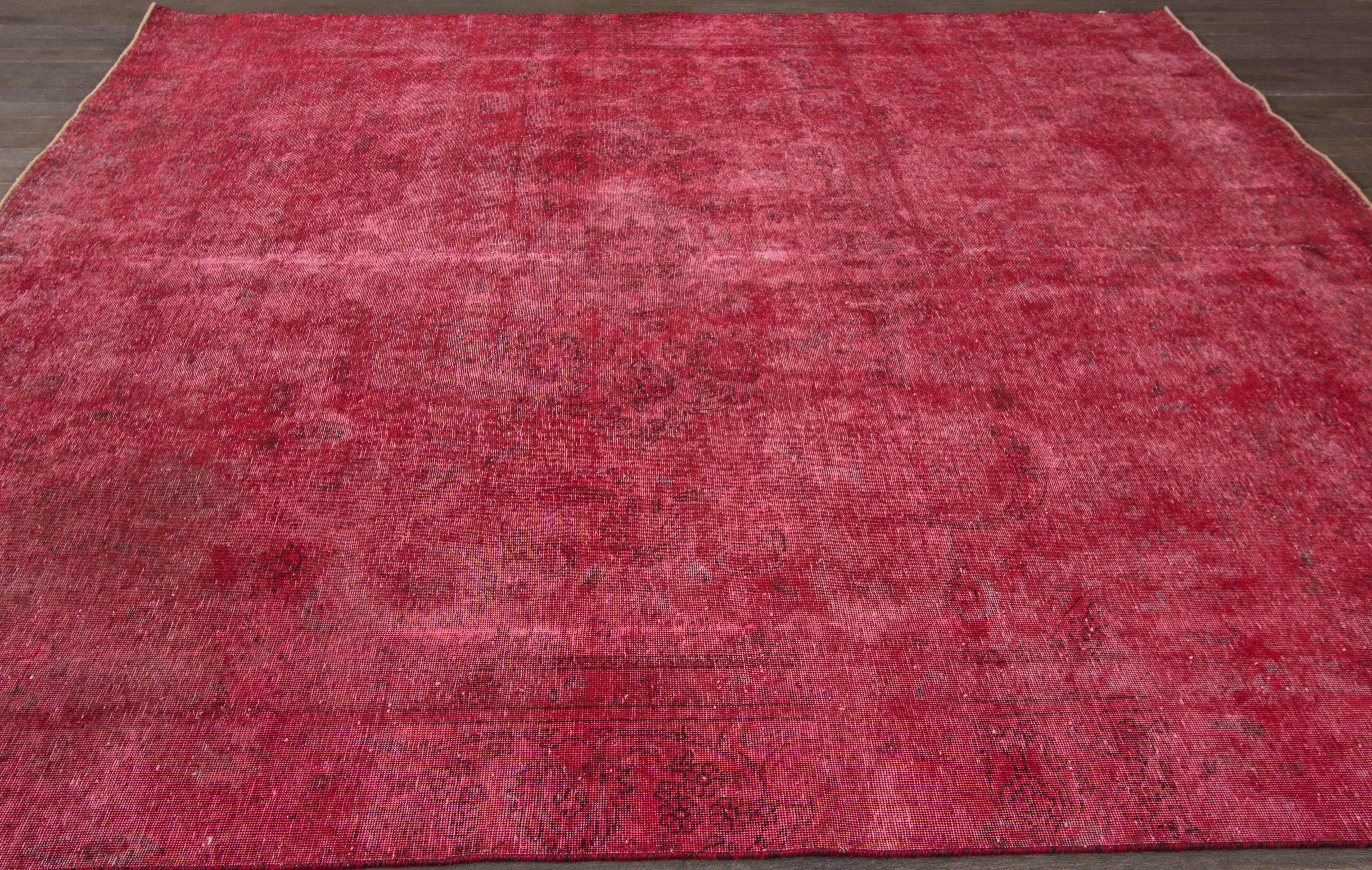 A hand-knotted square Overdyed rug with an all-over design on a red field. Accents of ivory and pink throughout the piece. This rug measures 8'.6 x 9'.7.