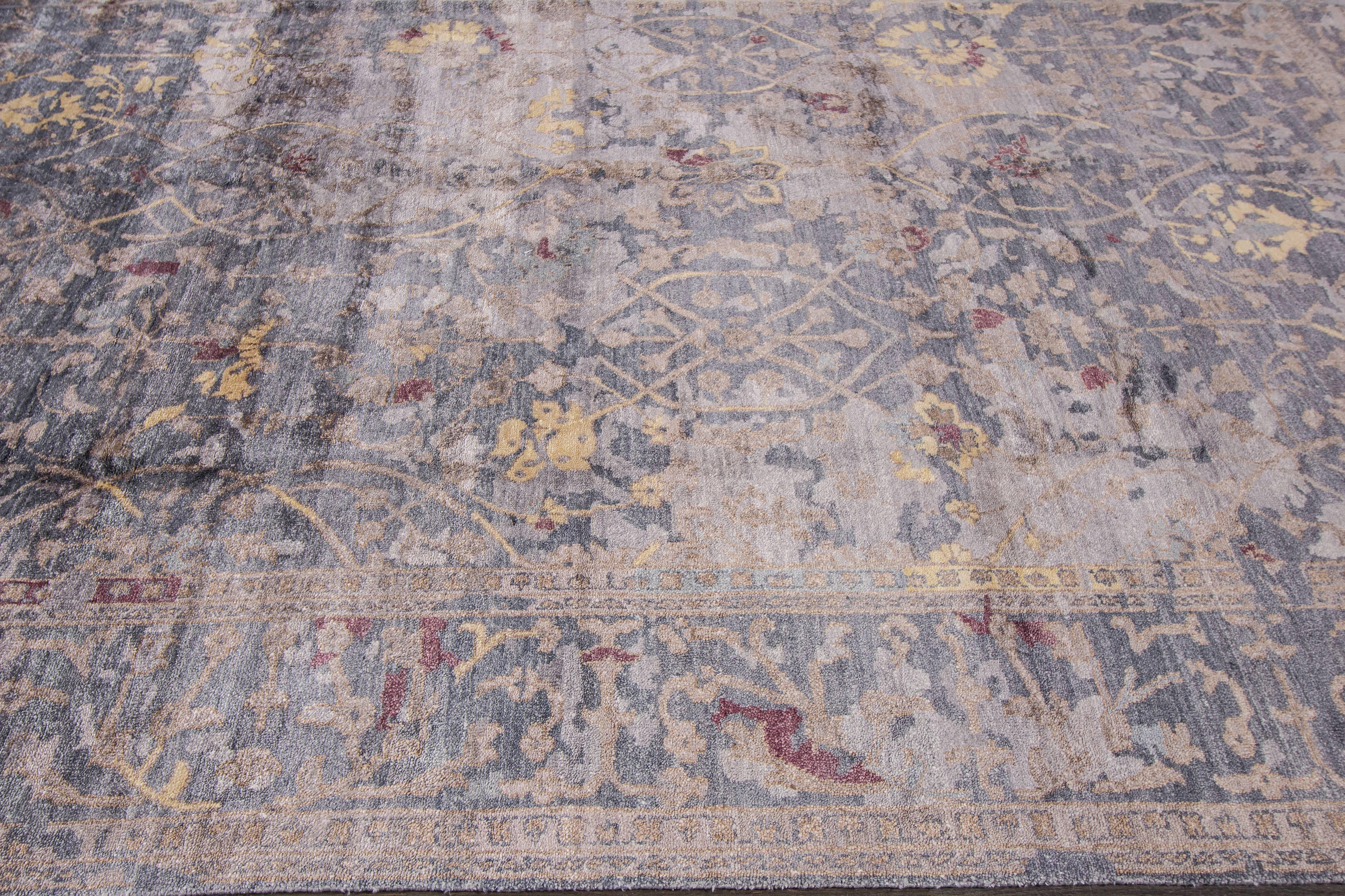 A hand-knotted modern Indian bamboo silk rug with a floral design on a gray field. Accents of beige and red throughout the piece. This rug measures 9' x 12'.