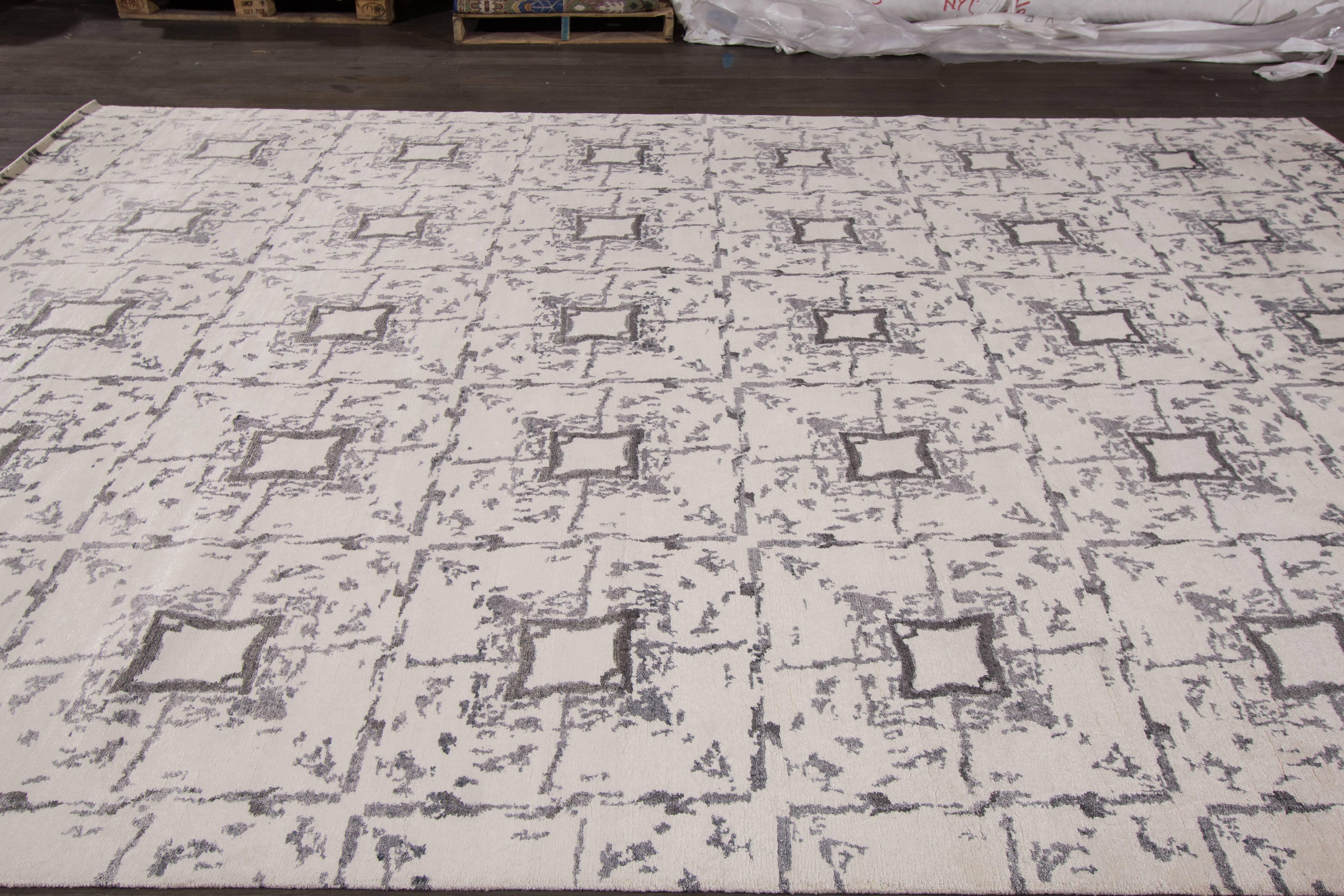 A hand-knotted modern Indian rug with a geometric design on a ivory field. Accents of grey throughout the piece. This rug measures 9'.8 x 14'.2.