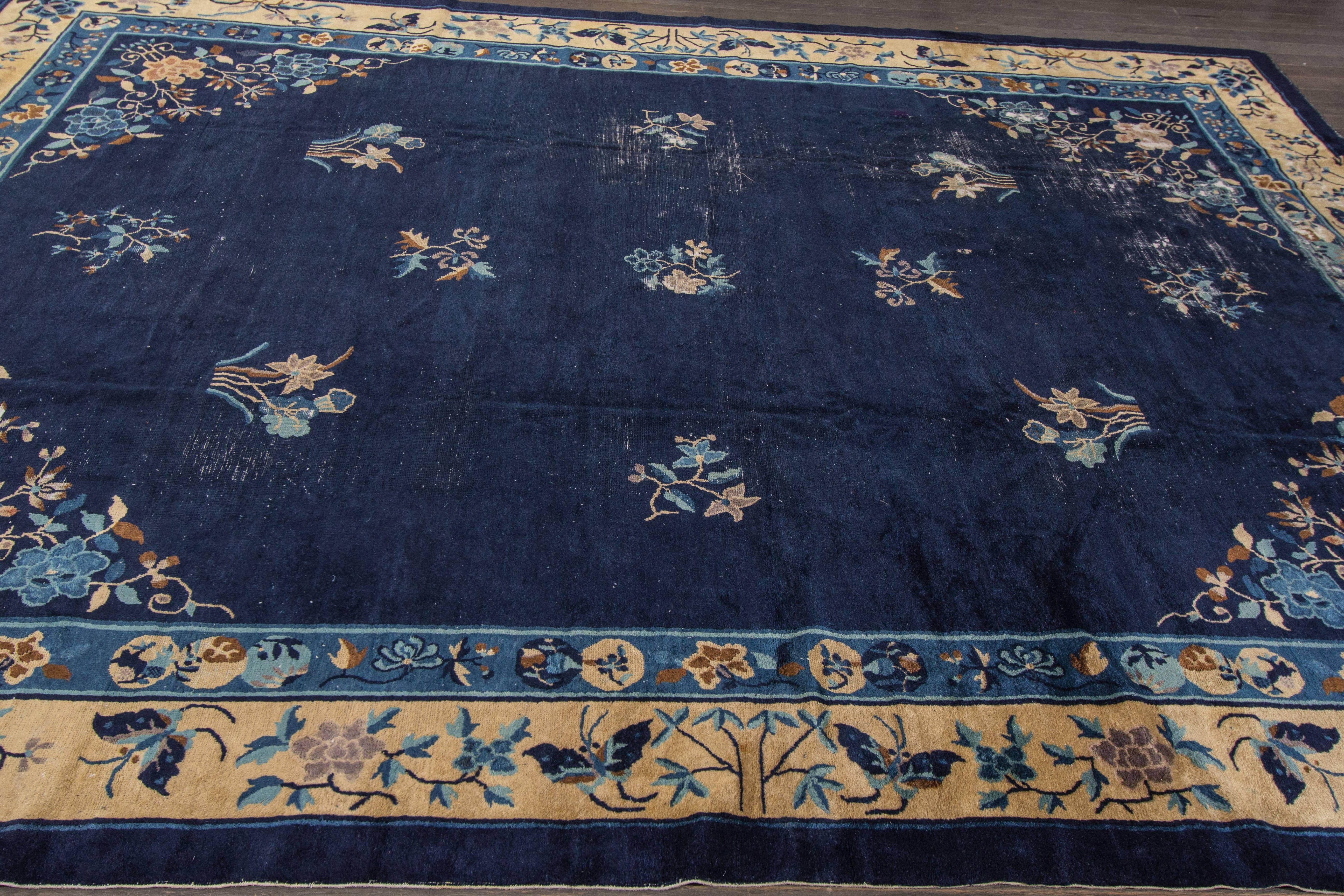 A hand-knotted Peking rug with a floral design on a blue field. Accents of beige, brown and red throughout the piece. This rug measures 8'.2 x 11'.6.