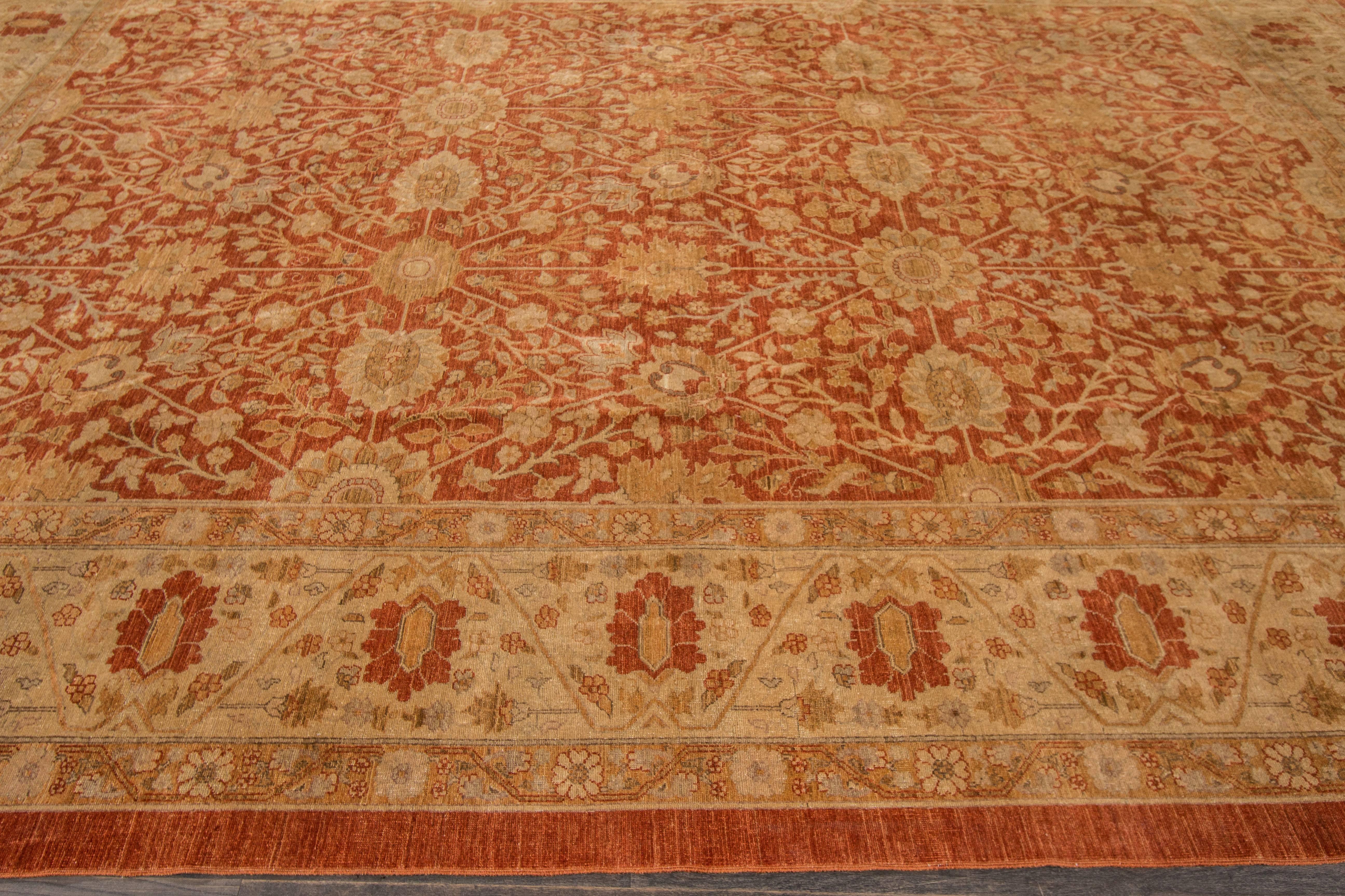 Un tappeto Tabriz annodato a mano con un disegno floreale su campo rosso. Accenti di marrone e beige in tutto il pezzo. Questo tappeto misura 9'.11 x 13'.6.