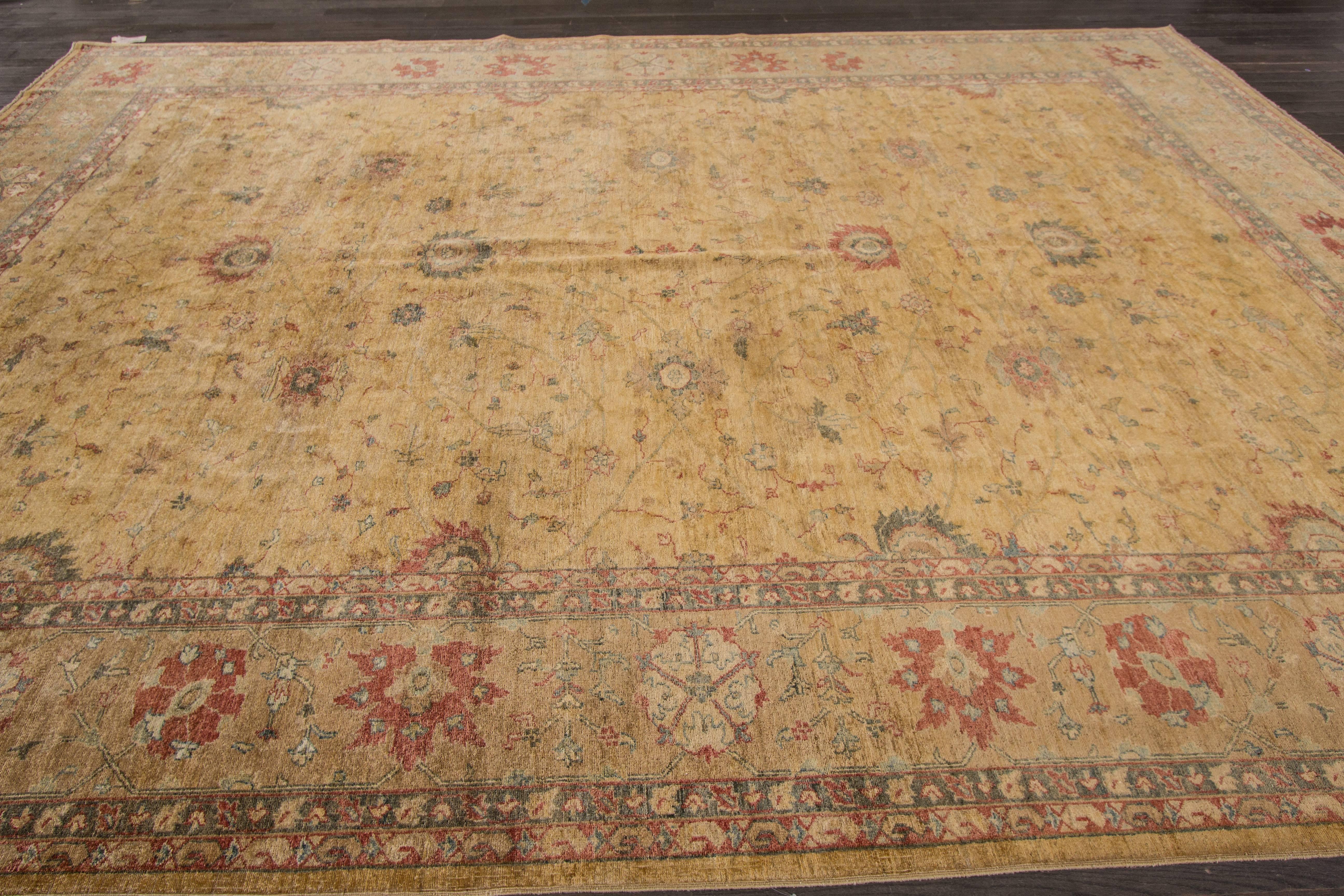 A hand-knotted Peshawar rug with a geometric design on a beige field. Accents of red, blue and ivory throughout the piece. This rug measures 10' x 14'.