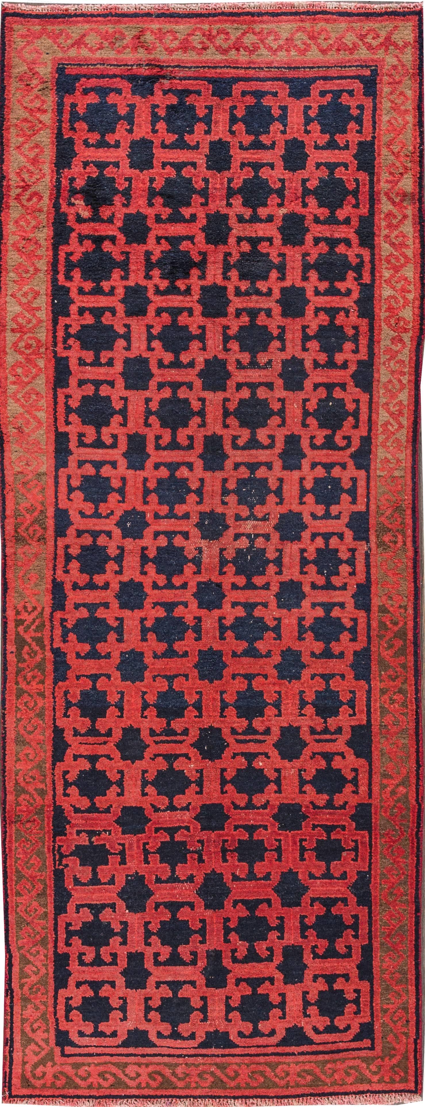 1920's Turkish Khotan carpet with a red field and blue geometric, measures approximately 4 feet 1 inch by 8 feet 6 inches. 