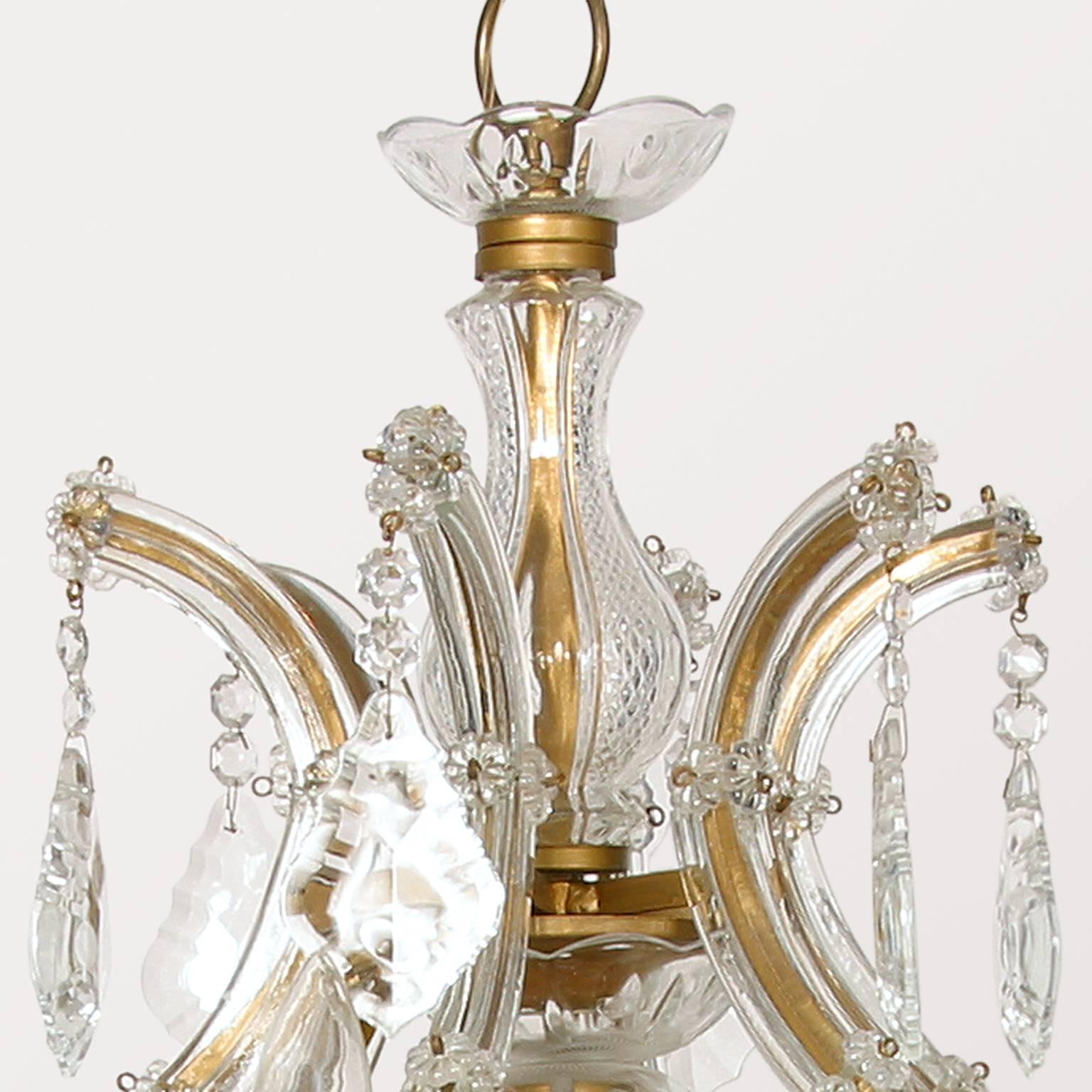 Italian sixteen-light (two-tier 15 light with one light in the middle) Maria Theresa Chandelier dating from the mid-1950s, lavishly laden with typical European cut crystal prisms, rosettes and beaded chain. Framework is gold painted with flat glass