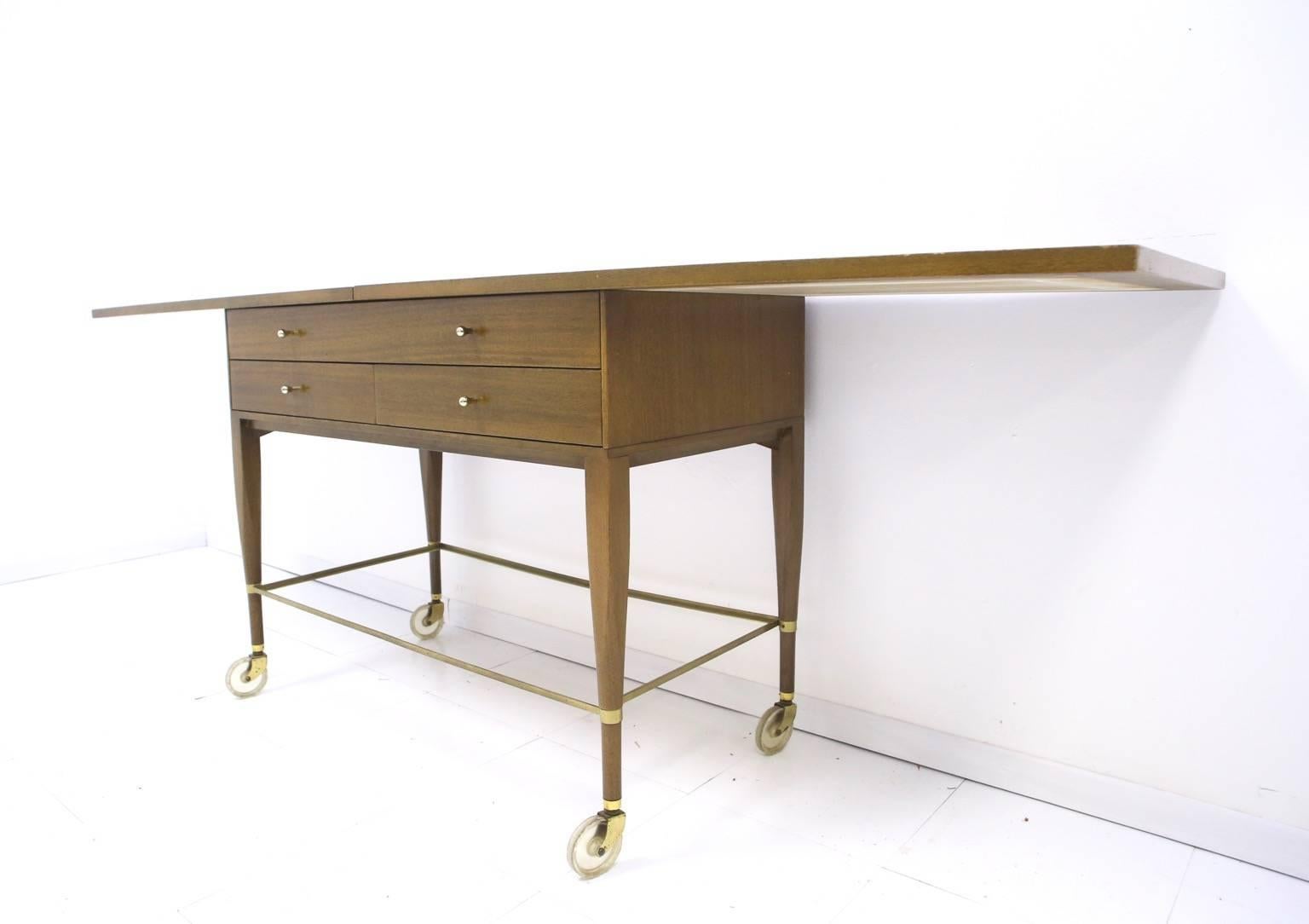 Very nice moveable serving cart by Paul McCobb for Calvin. Top has hinges that allow it to double in size. Sturdy construction of mahogany and brass with a brass framed glass shelf.