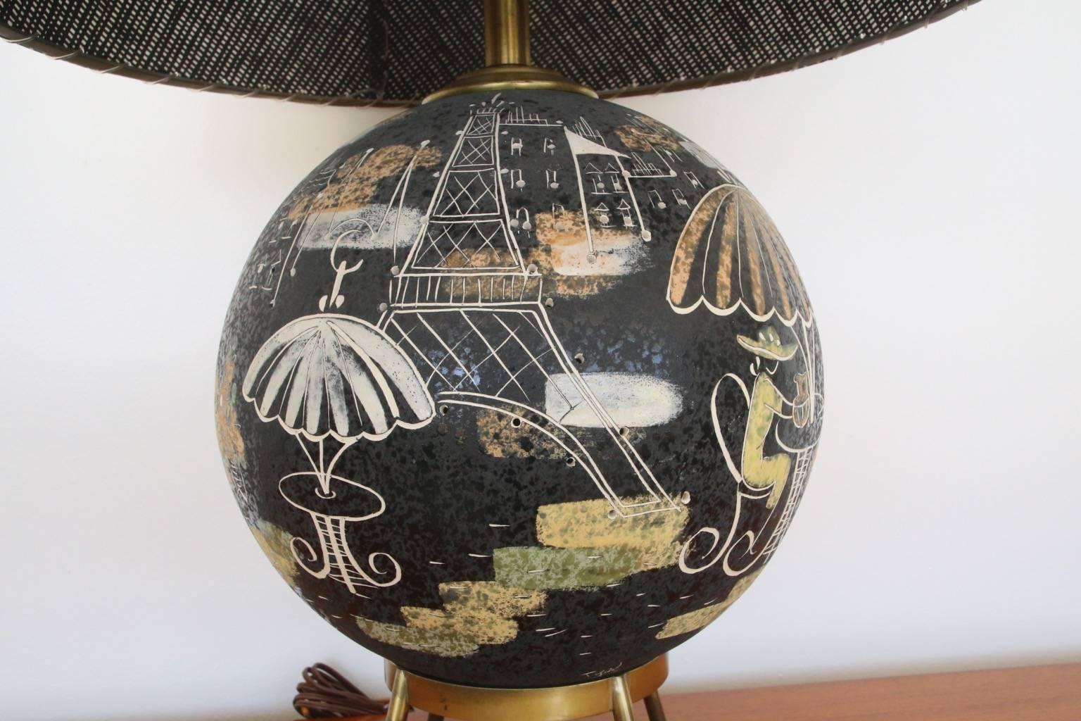 Very nice ceramic lamp by Tye of California. The sphere lights up to illuminate the city scene windows and sky. Eiffel tower and cafes. Fiberglass shade included.