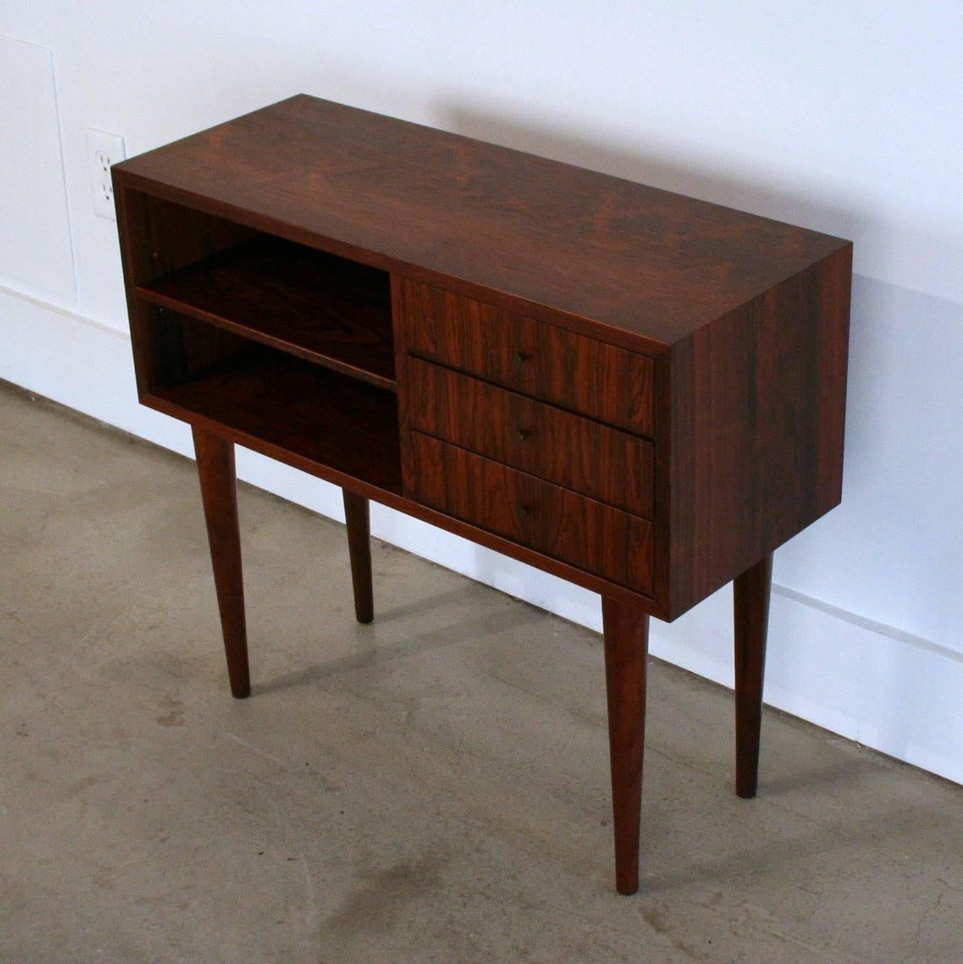 Incredible pair of Brazilian rosewood end tables. Small bank of three drawers beside open storage with an adjustable shelf. Resting on solid rosewood conical legs. Each end table mirrors each other to bookend a bed or sofa. Sold separately.