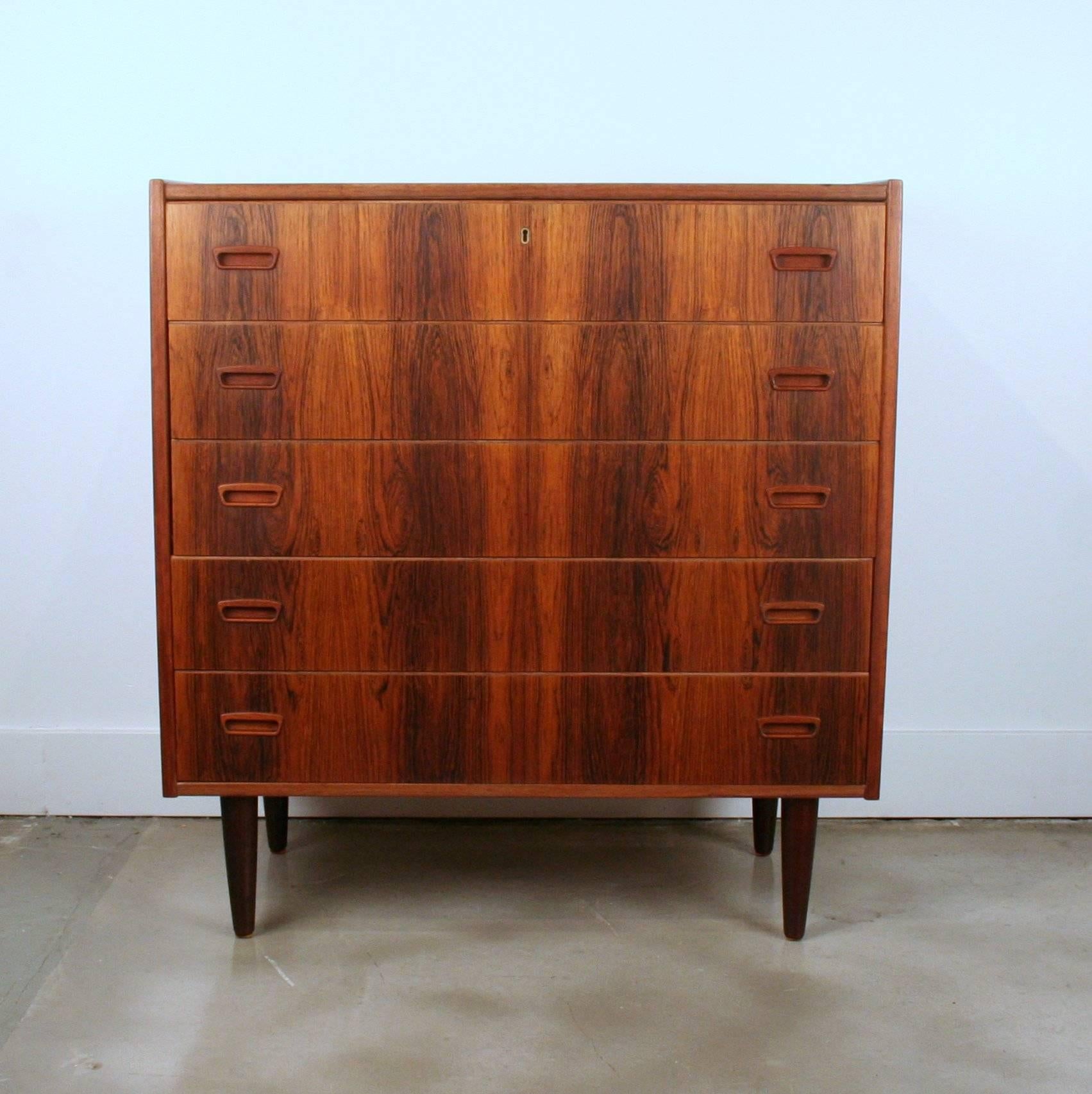 Vintage rosewood five-drawer dresser with exquisite graining throughout. Each drawer features two inset pulls and are constructed with dovetail joints. Set on four conical legs. Made in Denmark.