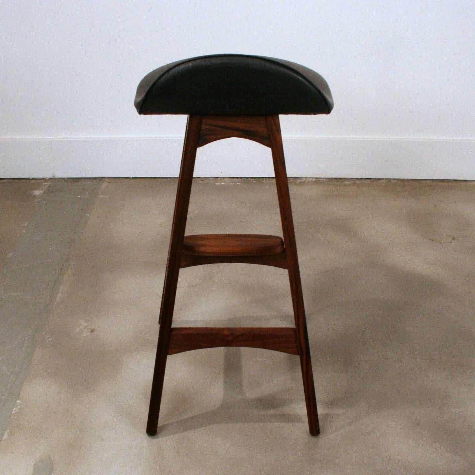 Vintage inspired bar stools by designer Erik Buck. Solid teak with beautiful graining and black vinyl seat. Made in Denmark. Measures: 27