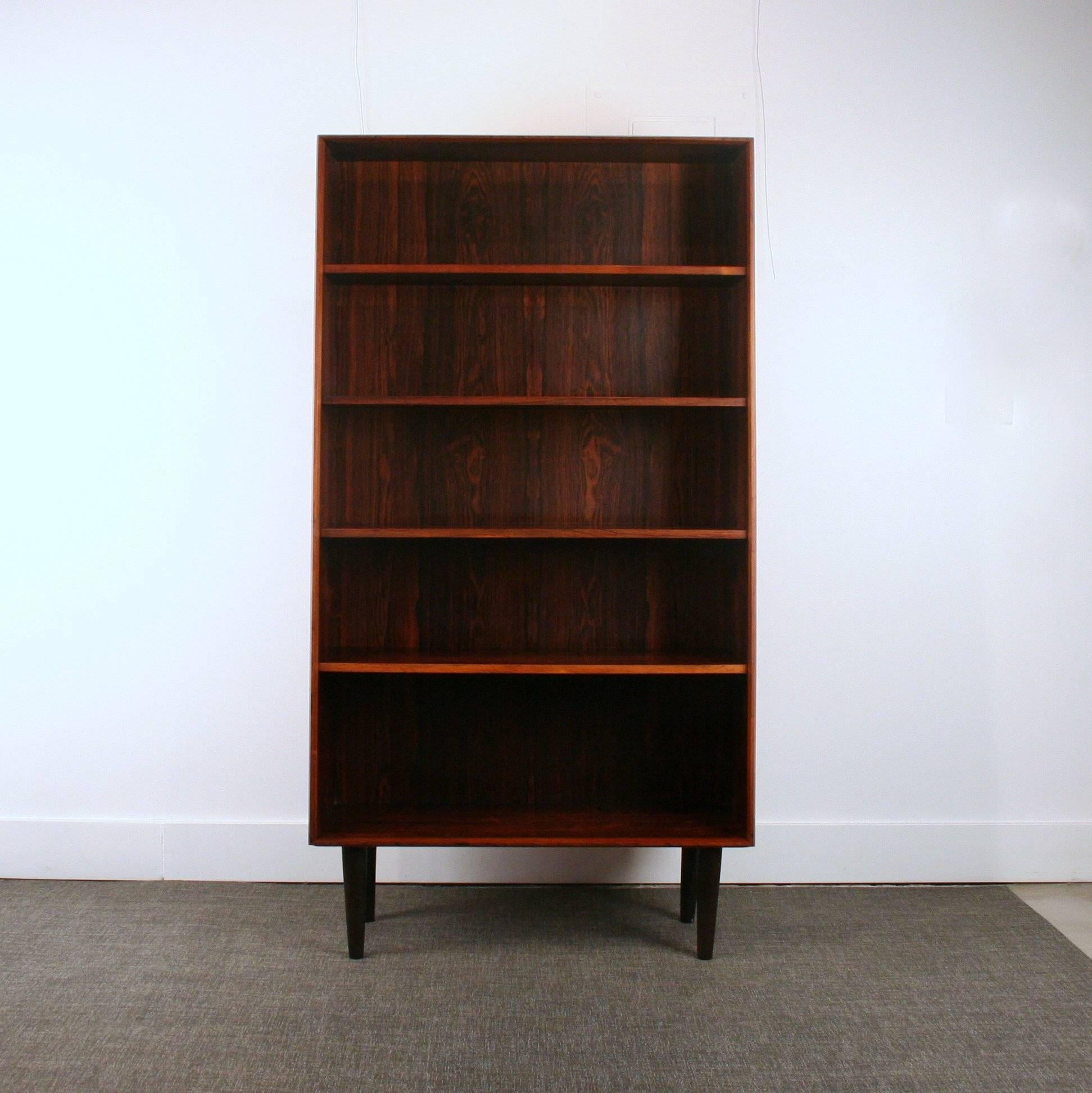 Absolutely stunning vintage rosewood bookcase set on four conical legs, features tapered side panels and four shelves.