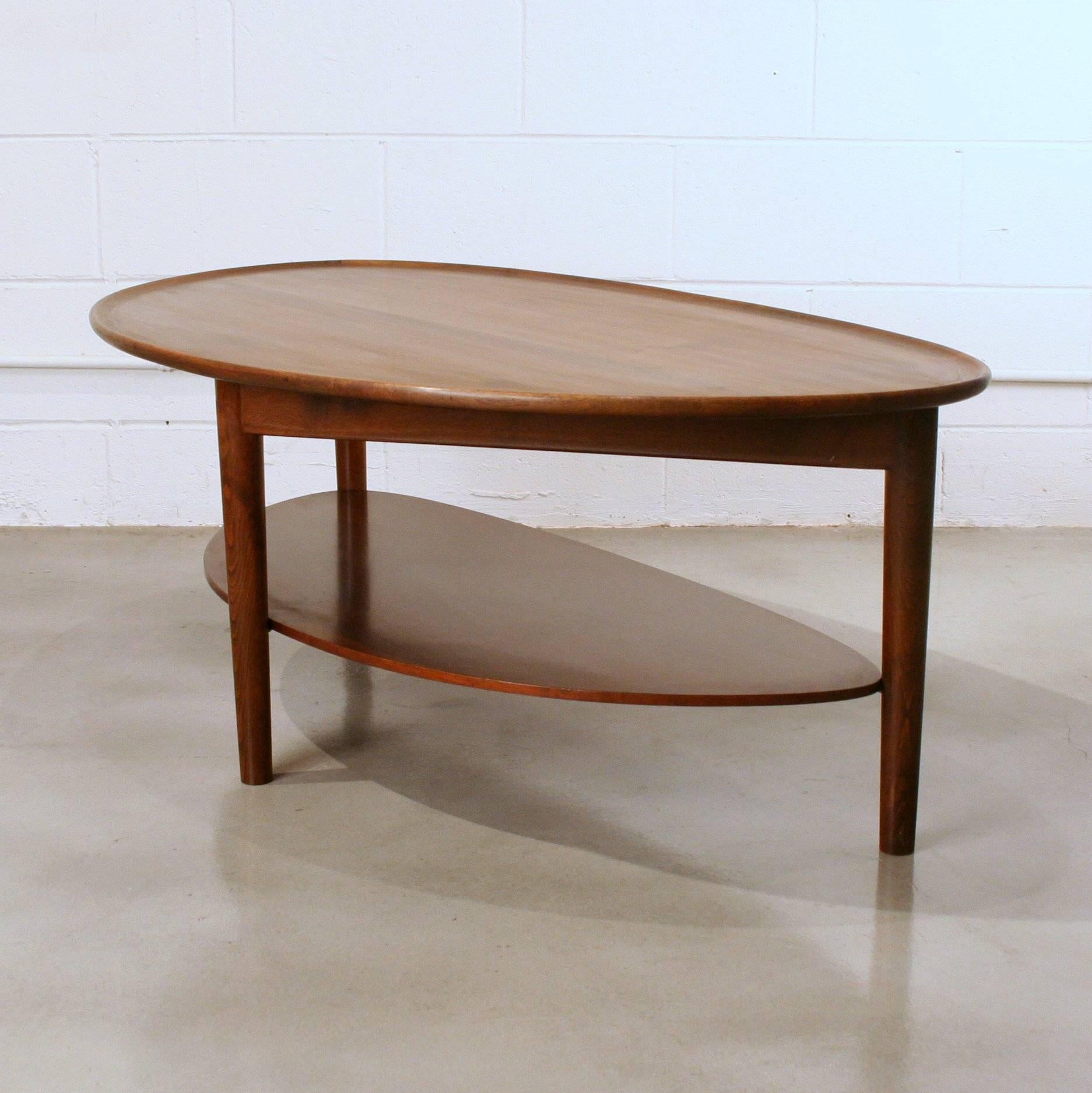 Vintage walnut coffee table in a kidney shape featuring a single shelf below the tabletop and a solid walnut tapered trim. Made in Denmark.
 